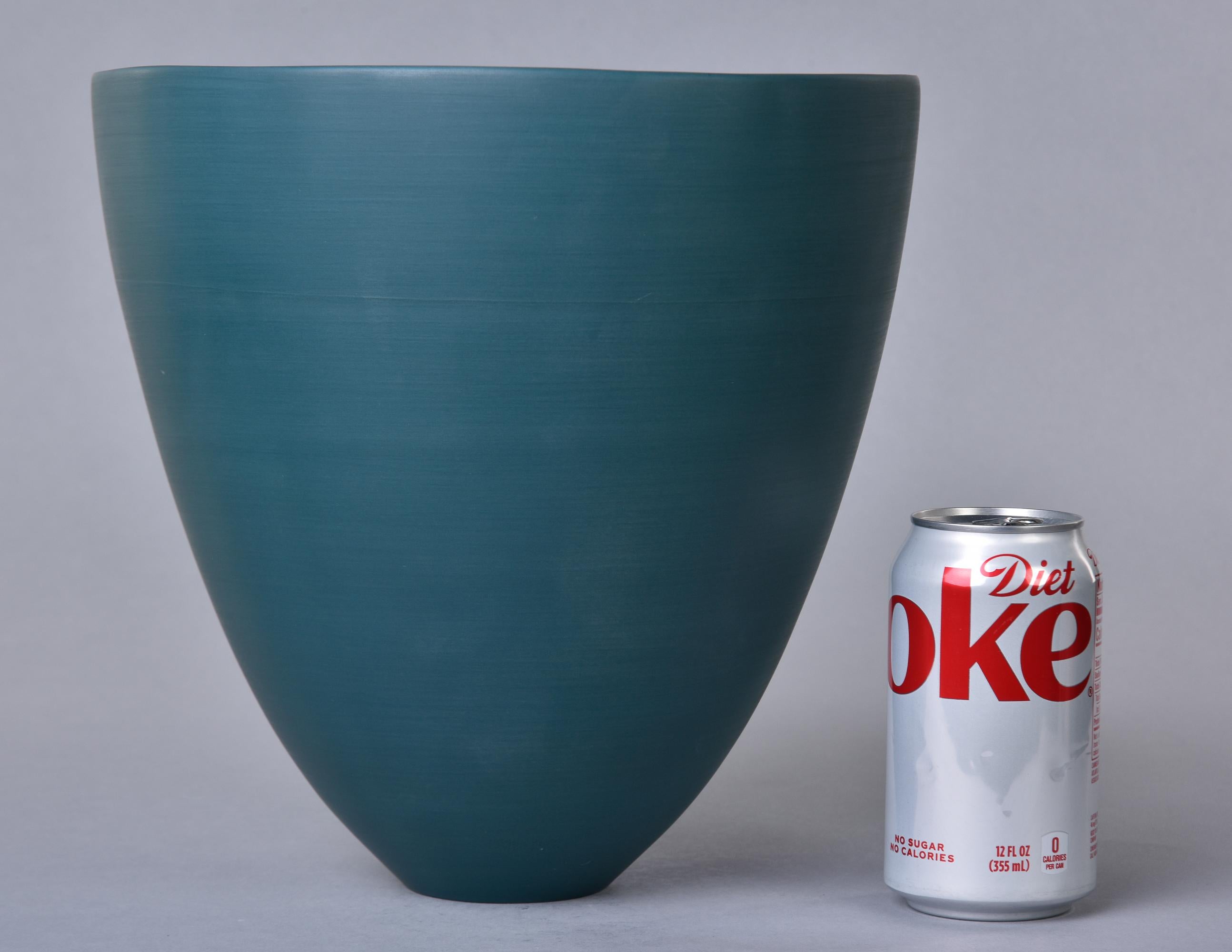Nouveau et fabriqué à la main en Italie par Rina Menardi, ce bol ou vase en forme de coupe mesure un peu moins de 11 pouces de haut et présente une glaçure vert sarcelle foncé. Forme aérodynamique avec de fines parois en porcelaine émaillée et le
