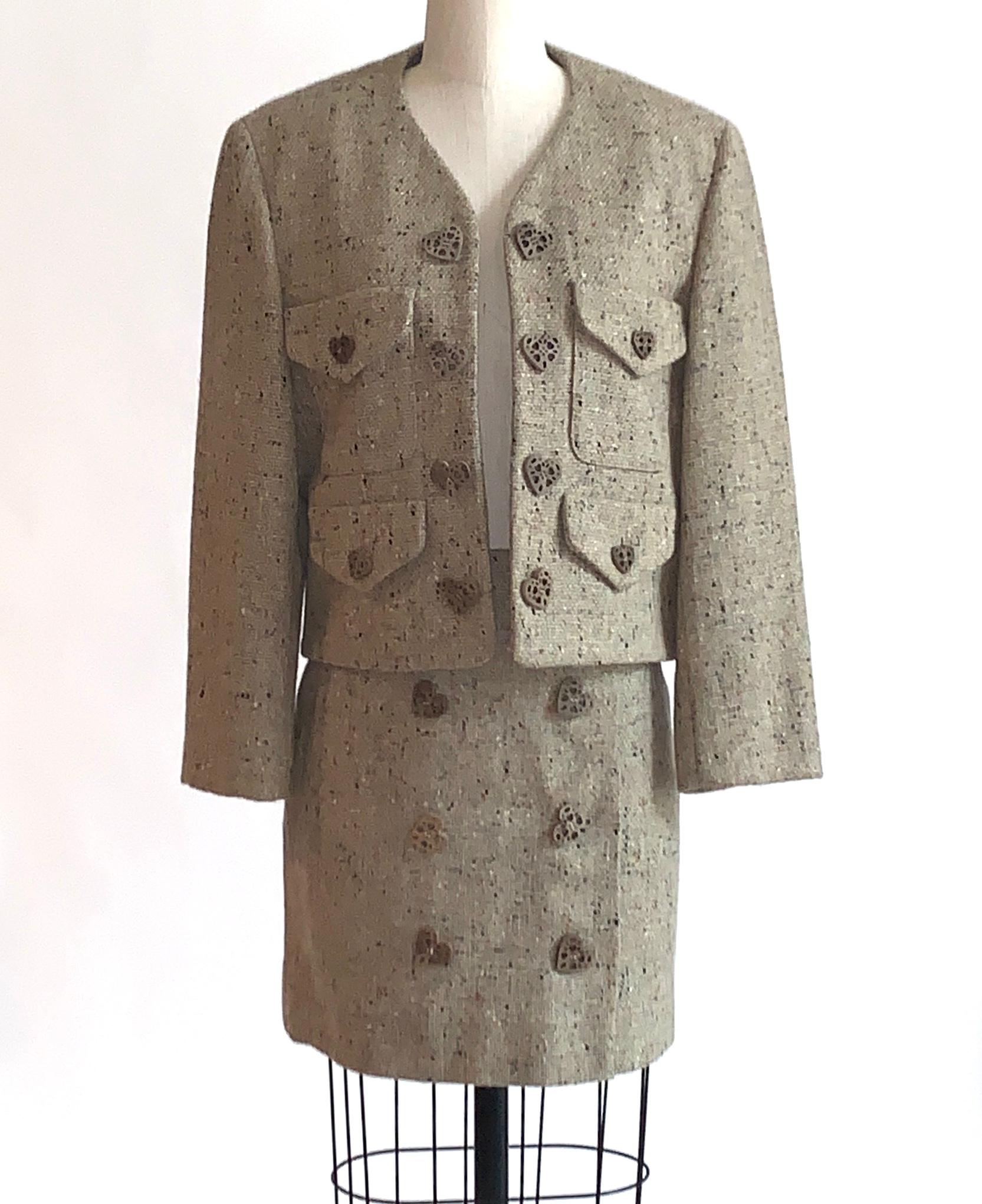 Vintage Moschino Cheap & Chic 1990s skirt suit in oatmeal tweed, speckled with flecks of orange, charcoal, and a very subtle pale lime. Open front jacket features front pockets with flaps and wooden heart buttons. Light padding at shoulders. Wrap