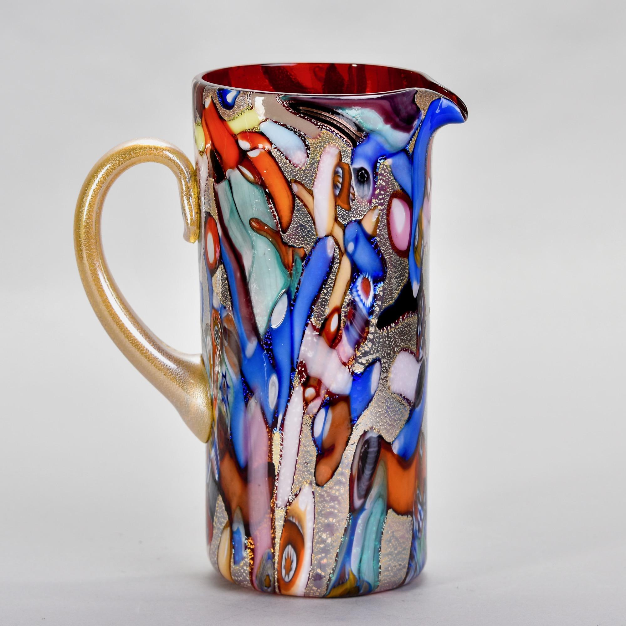 Found in Italy, this new Murano glass pitcher has a red interior and multiple colored exterior with prominent streaks of blue, orange, white, red and some scattered murrine flowers. Unknown maker. Versatile, decorative vessel than can be used as a