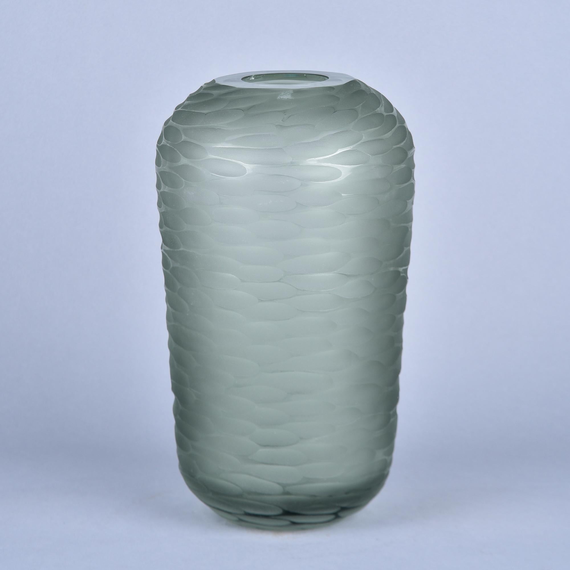 Neuf et fabriqué en Italie par un verrier inconnu de Murano, ce vase mesure 15 pouces de haut et 8,5 pouces de diamètre. Le lourd verre vert bouteille fumé pâle présente des détails de surface taillés et polis - appelés battuto en italien - qui