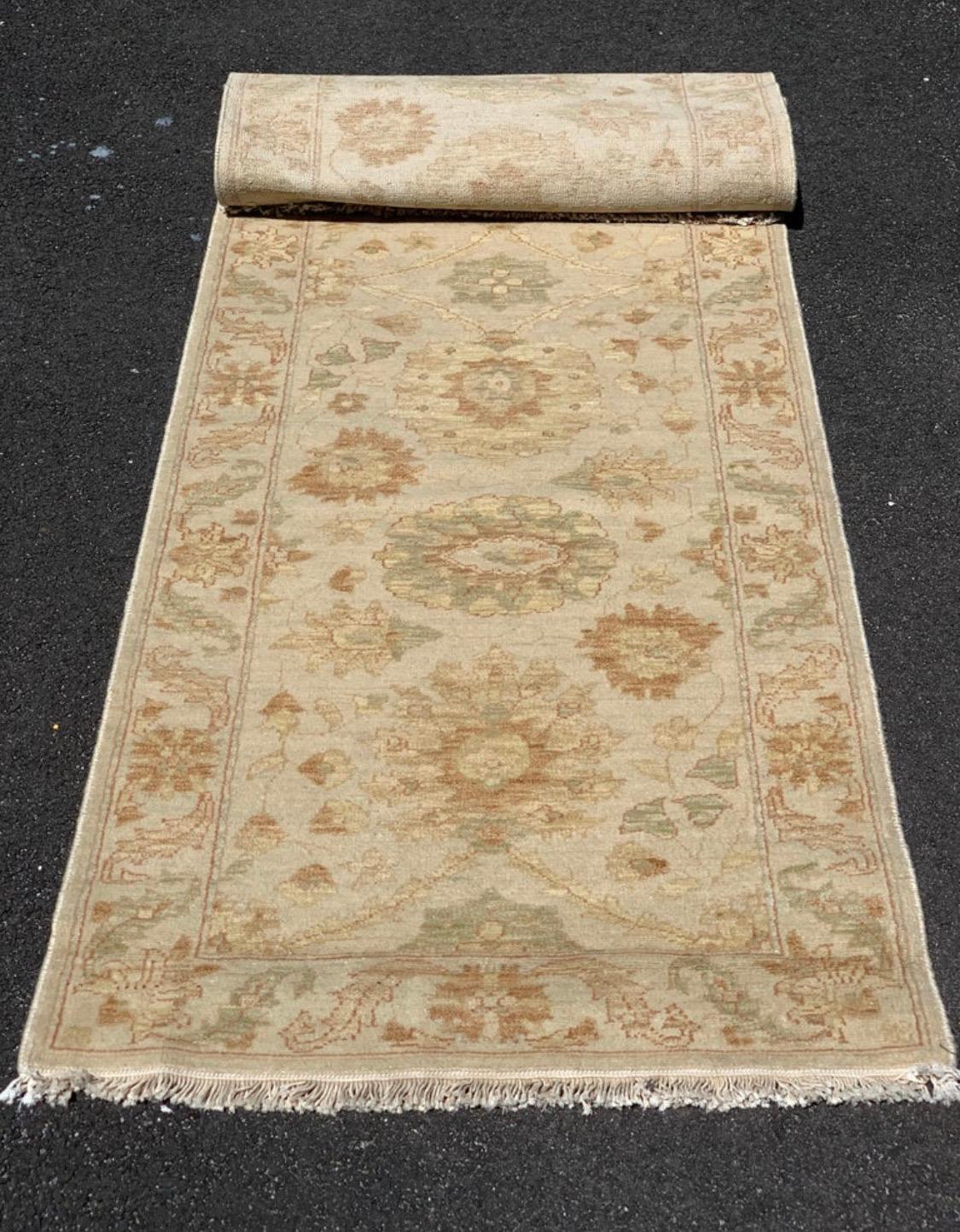 This is a new late 20th century long and narrow beige ivory floral Persian style runner rug handwoven in Alexandria, Egypt in 1990s. We manufactured these rugs and the design and colors were hand chosen by us and we have a wide variety of sizes in