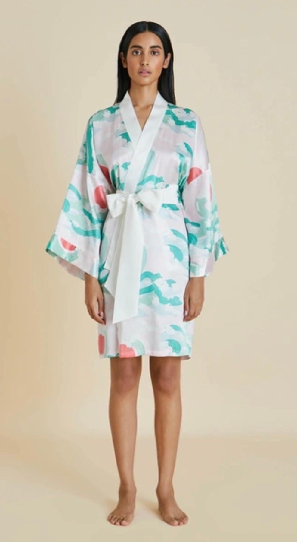 Die Robe von Olivia von Halle ist aus weichem Seidensatin in einer von Kimono inspirierten Silhouette gefertigt. Es ist ganzflächig mit einem japanisch inspirierten Motiv in Rosa-, Korallen- und Meerschaumgrüntönen bedruckt. Es hat weite Ärmel und