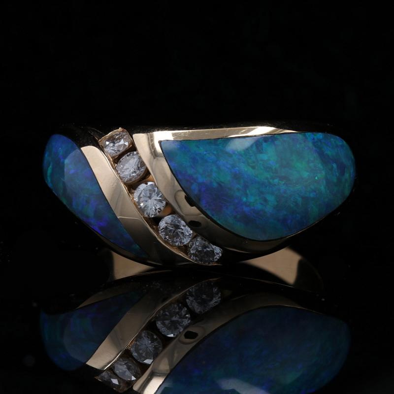 Make this gorgeous ring your signature piece! Fashioned by Kabana in 14k yellow gold, this NEW piece features a modified bypass-style band adorned in the center with a swirl of five channel-set diamonds. Inlaid opals with fabulous blue-green