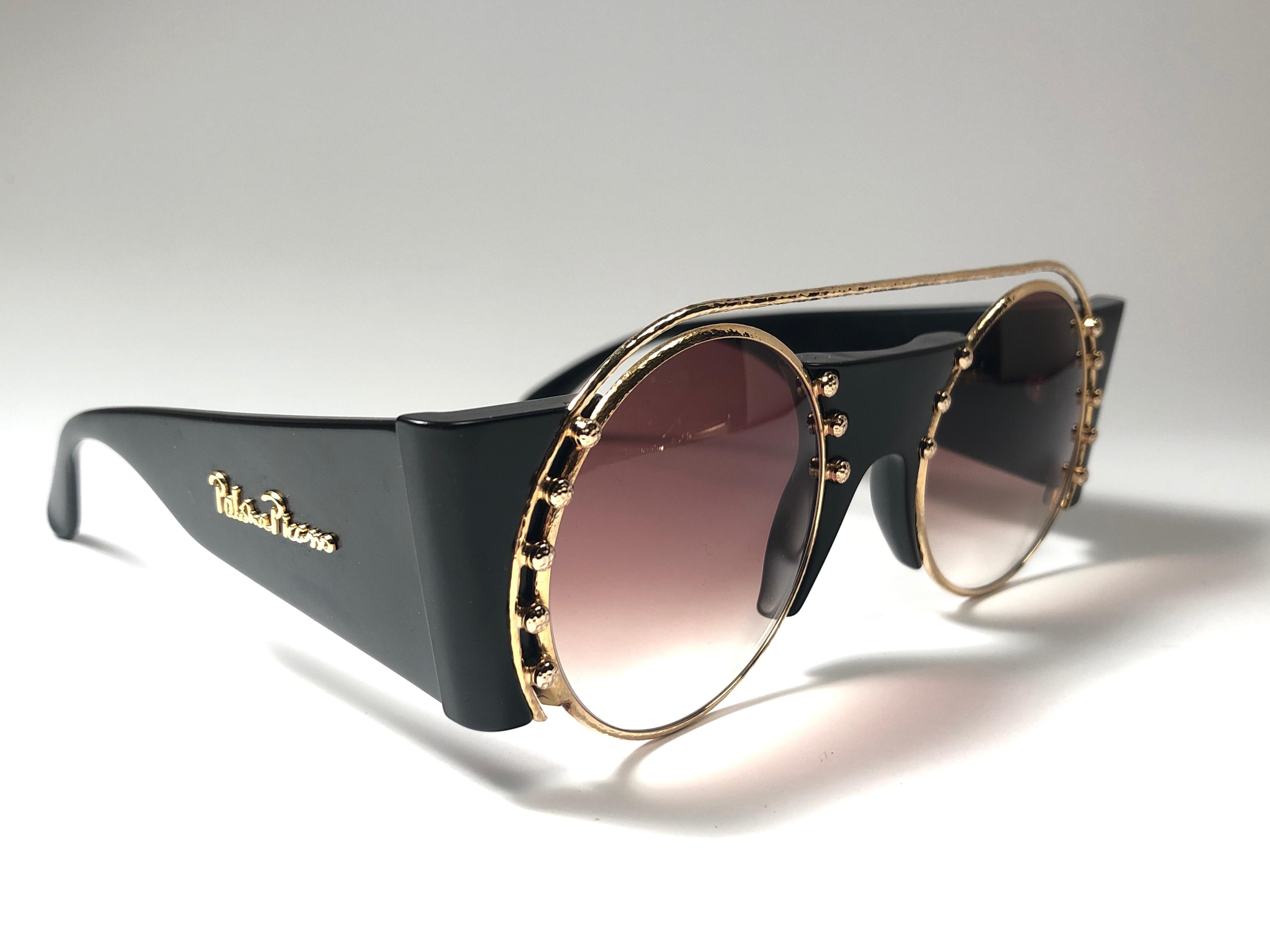 New Vintage Paloma Picasso black and gold frame with strass details sunglasses.

Made in Germany 1980's. 

Frame with minor wear and tarnish due to storage. 

Made in Germany.