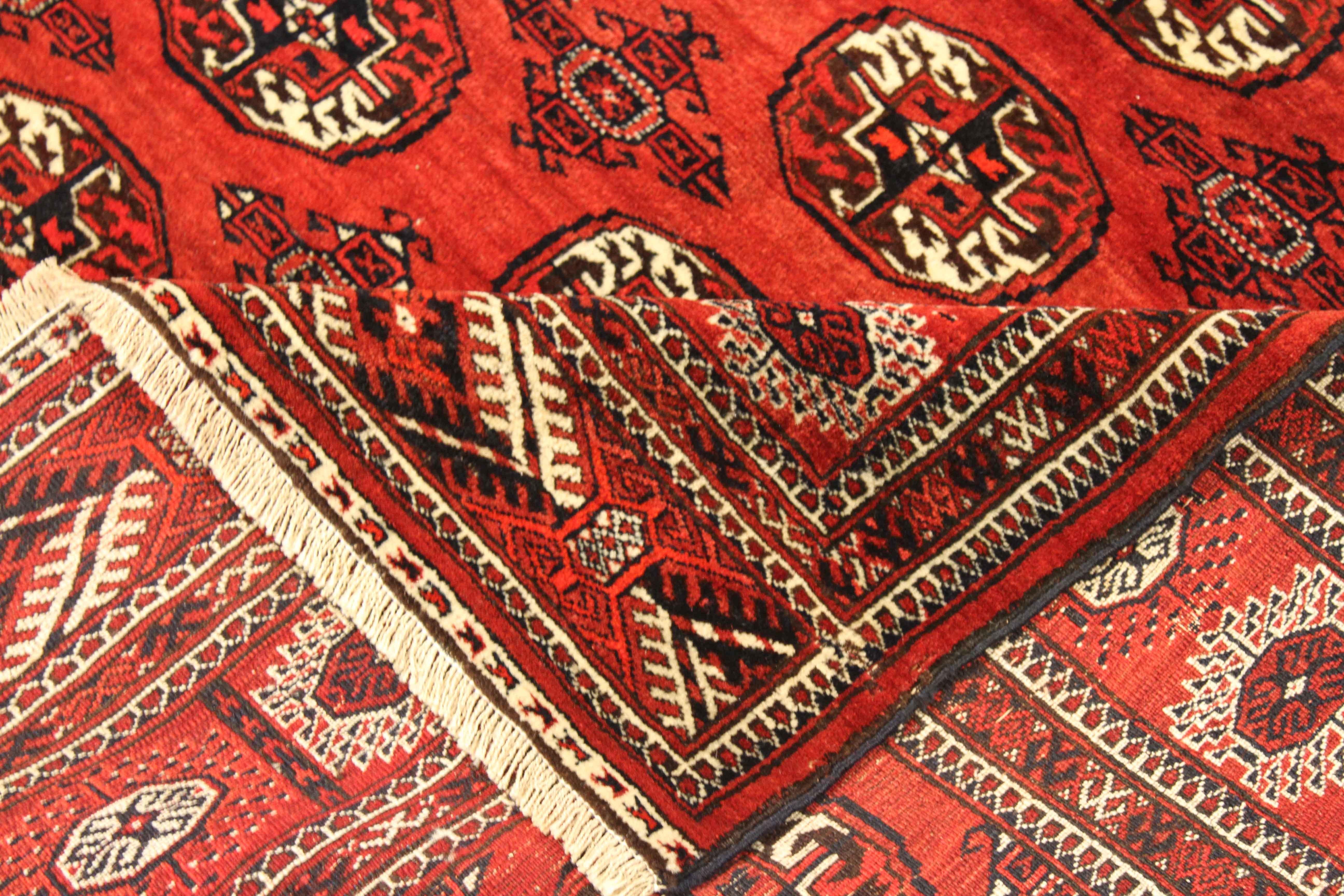 New Persian rug handwoven from the finest sheep’s wool and colored with all-natural vegetable dyes that are safe for humans and pets. It’s a traditional Turkmen design featuring ‘Gul’ or rose-like details in black and ivory over a deep red field. It