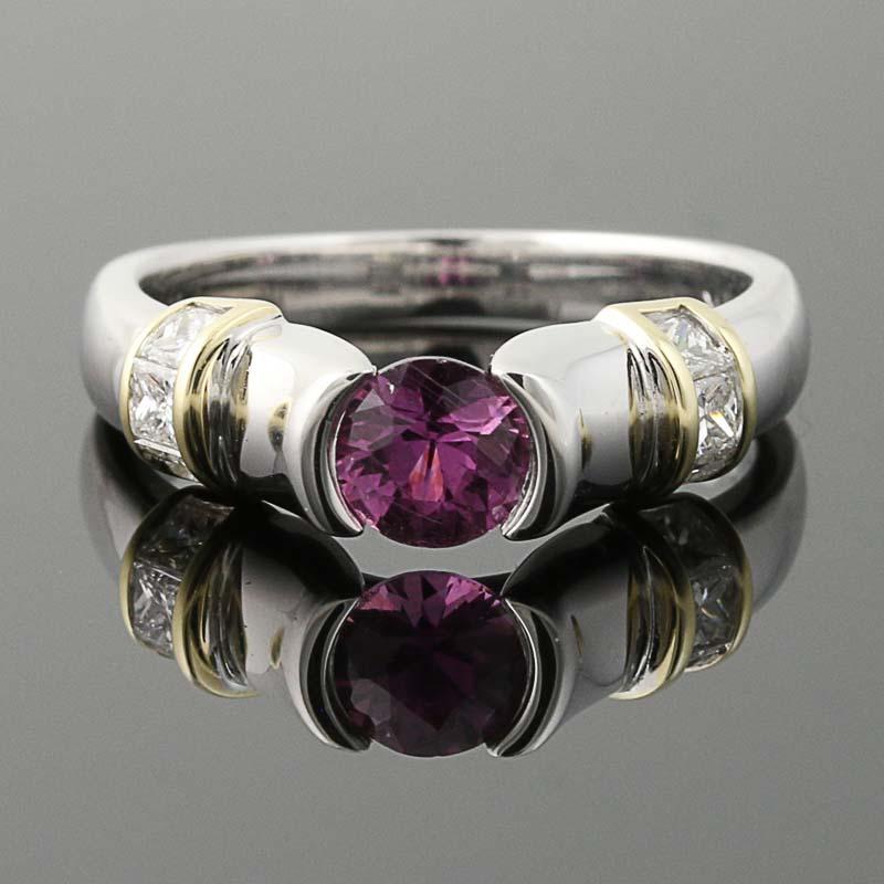 Modern elegance defined! Crafted in 14k white and yellow gold, this NEW ring showcases a berry pink sapphire solitaire held in a half-bezel mount that is adorned with glittering princess cut diamond accents for a stunning display from every angle.