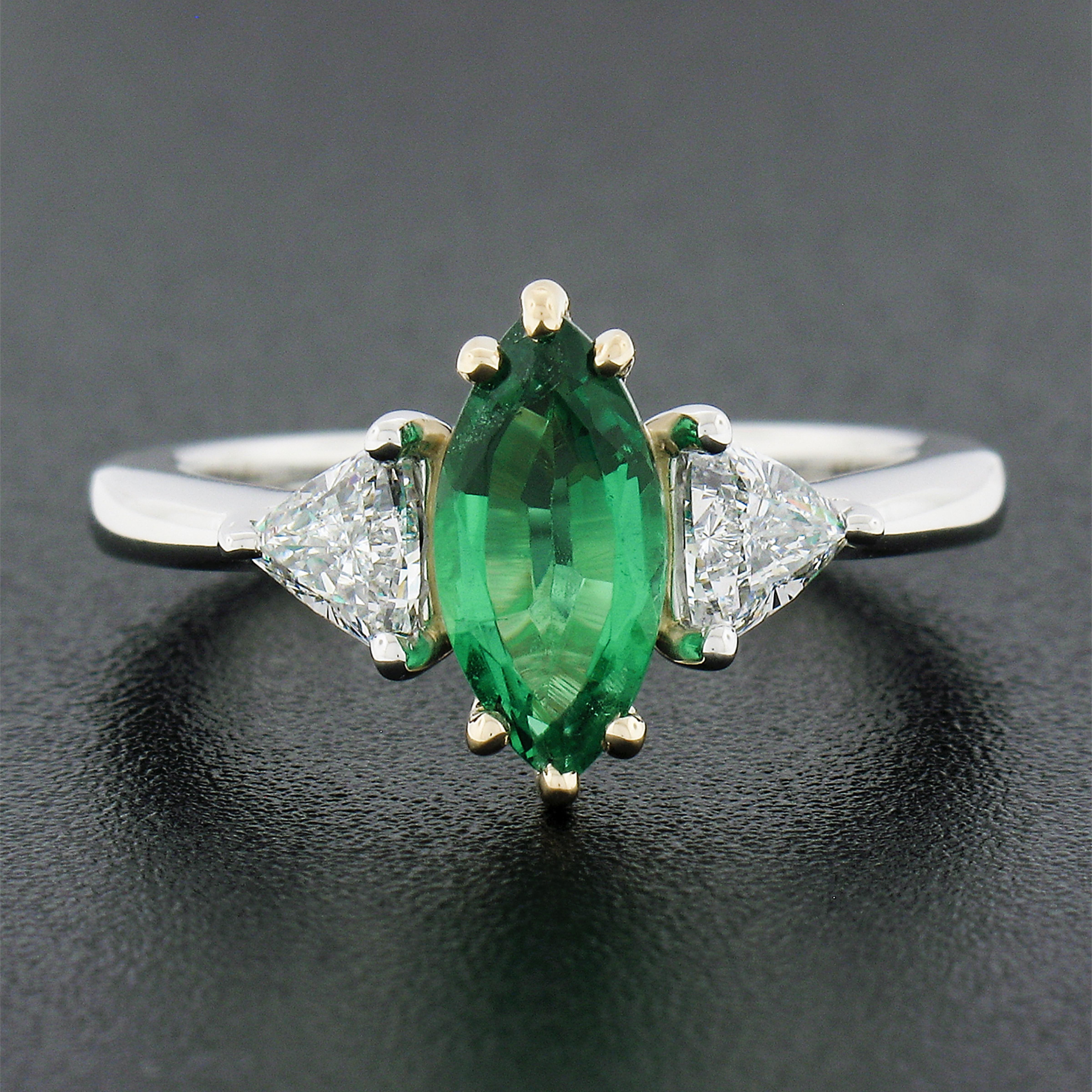 Here we have a magnificent emerald and diamond three-stone ring that is crafted in solid platinum with an 18k yellow gold center that features a gorgeous, GIA certified, natural emerald stone. The solitaire displays a very clean and truly incredible