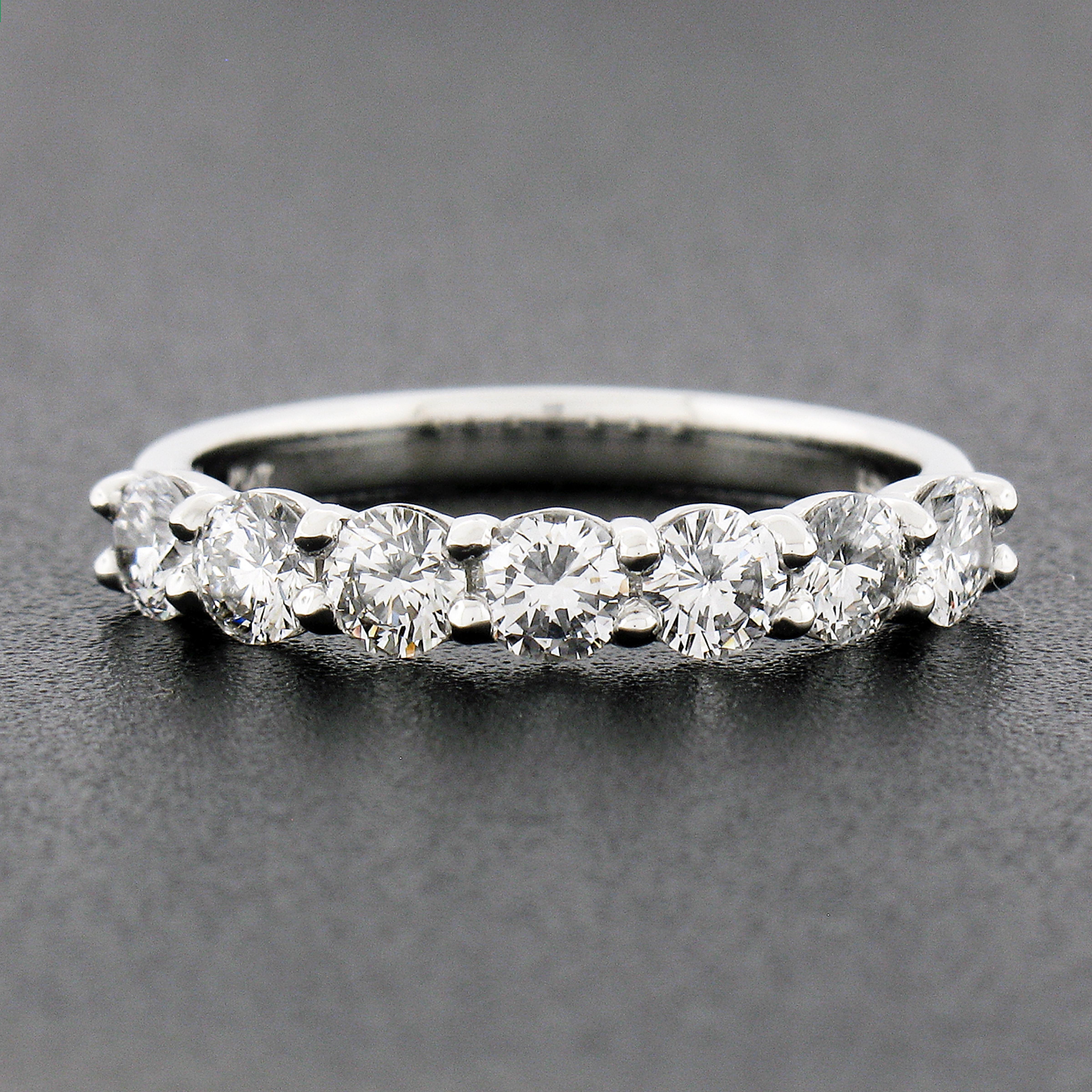 This classic and stunning diamond band ring is newly crafted from solid platinum and features 7 round brilliant cut diamonds neatly shared-prong set across its top. The diamonds weigh exactly 1.12 carats total, with each showing a nice large size,