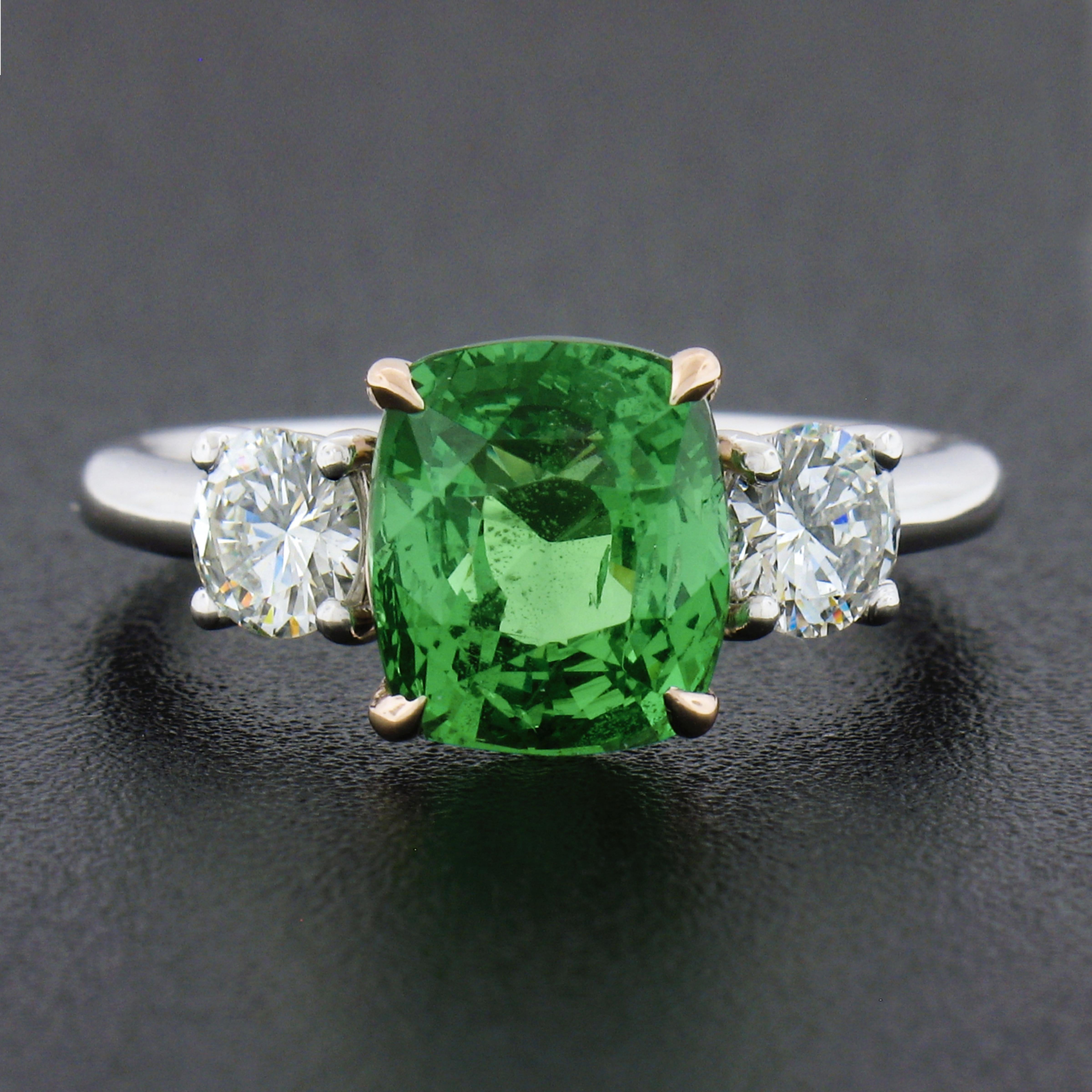Here we have a fancy, and truly magnificent green tsavorite and diamond cocktail ring newly crafted in solid platinum with a solid 14k rose gold center basket setting. The ring features a natural, GIA certified, cushion cut green tsavorite that