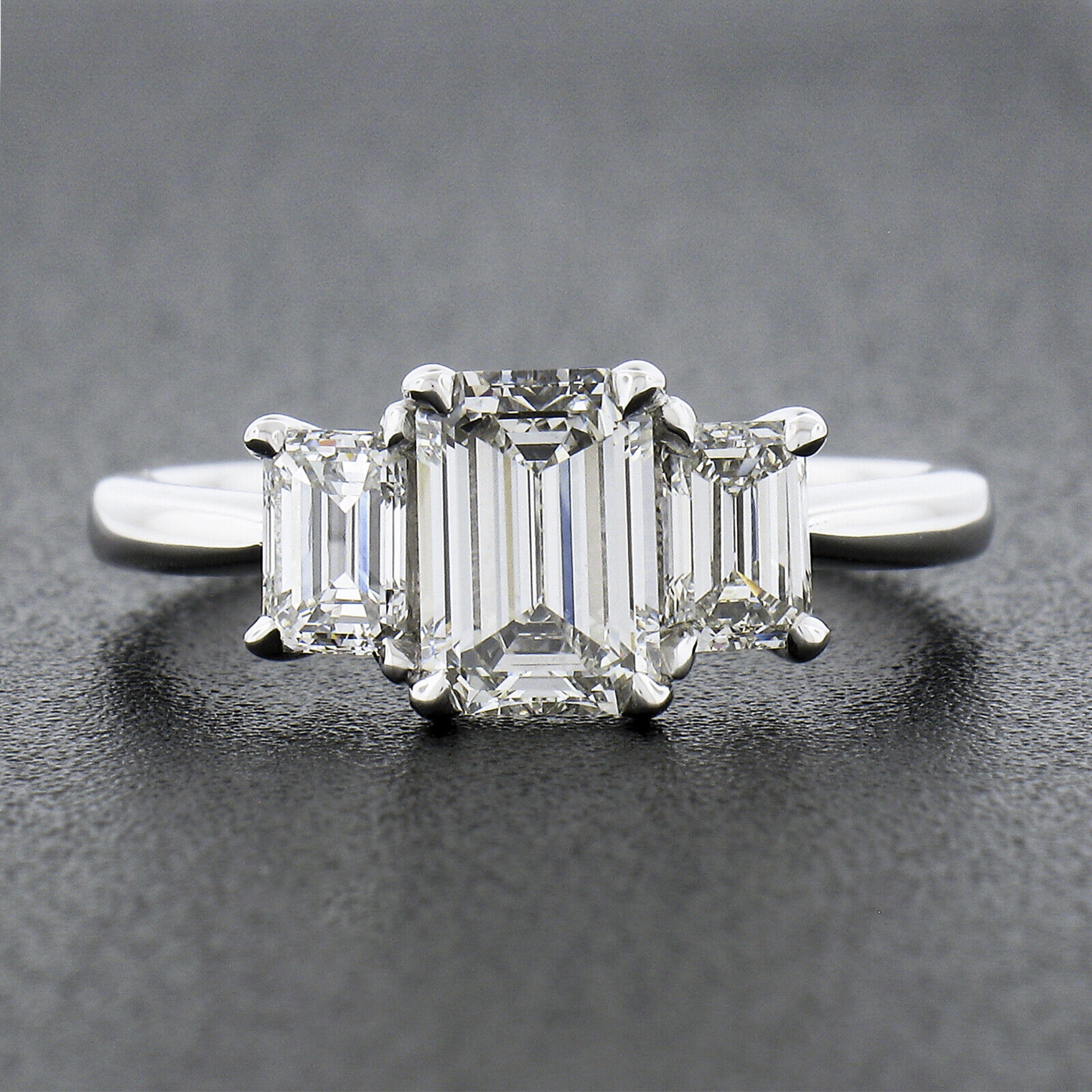 You are looking at a brand new and truly magnificent engagement style ring that was crafted from solid platinum. This incredible three stone ring features an absolutely breathtaking, GIA certified, emerald cut diamond neatly set with claw prongs at