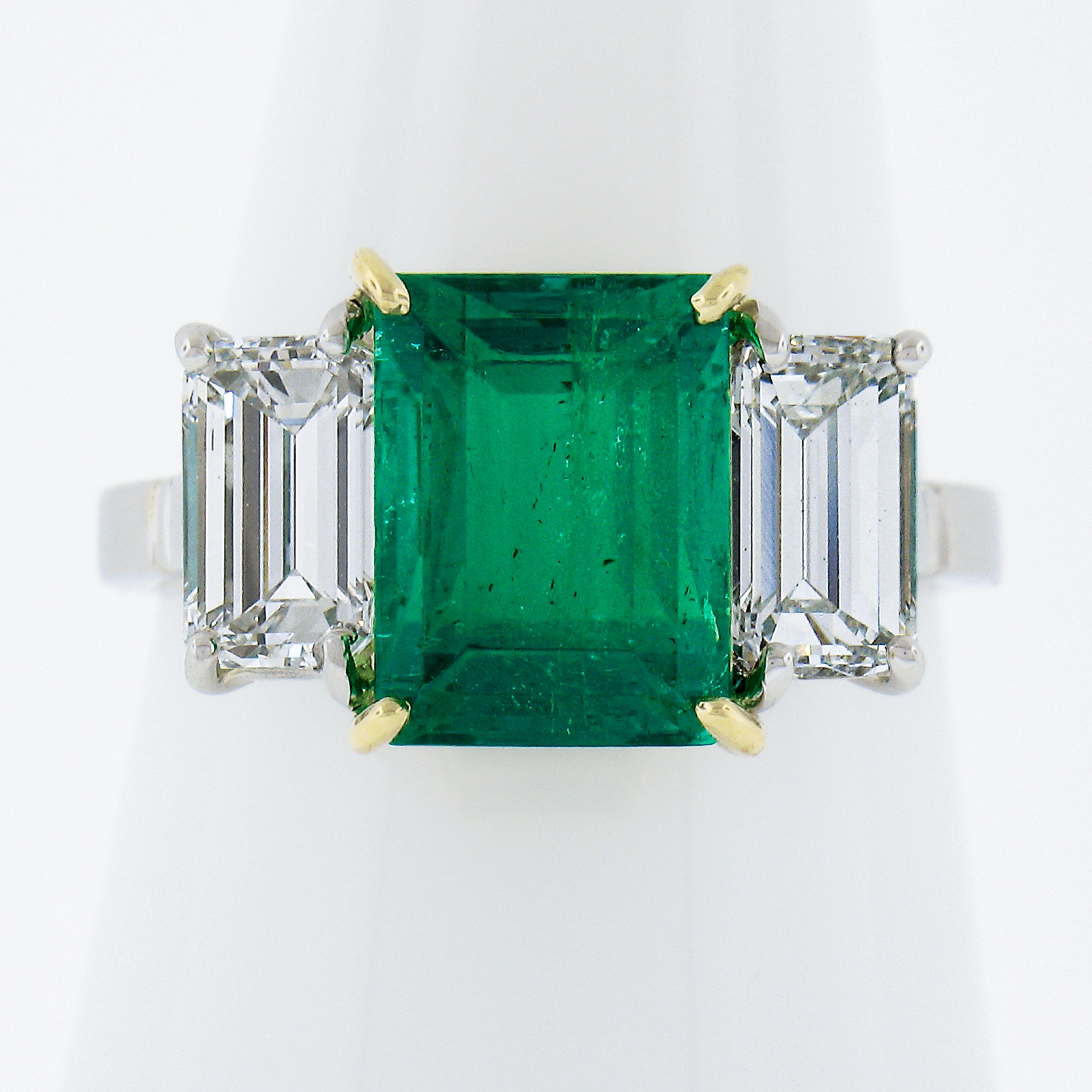 This elegant and timeless custom made ring centers a wonderful Colombian emerald with minor oil only! On either side is a gorgeous elongated emerald cut diamond - GIA graded as colorless and VS clarity. This ring comes with 3 certifications and high