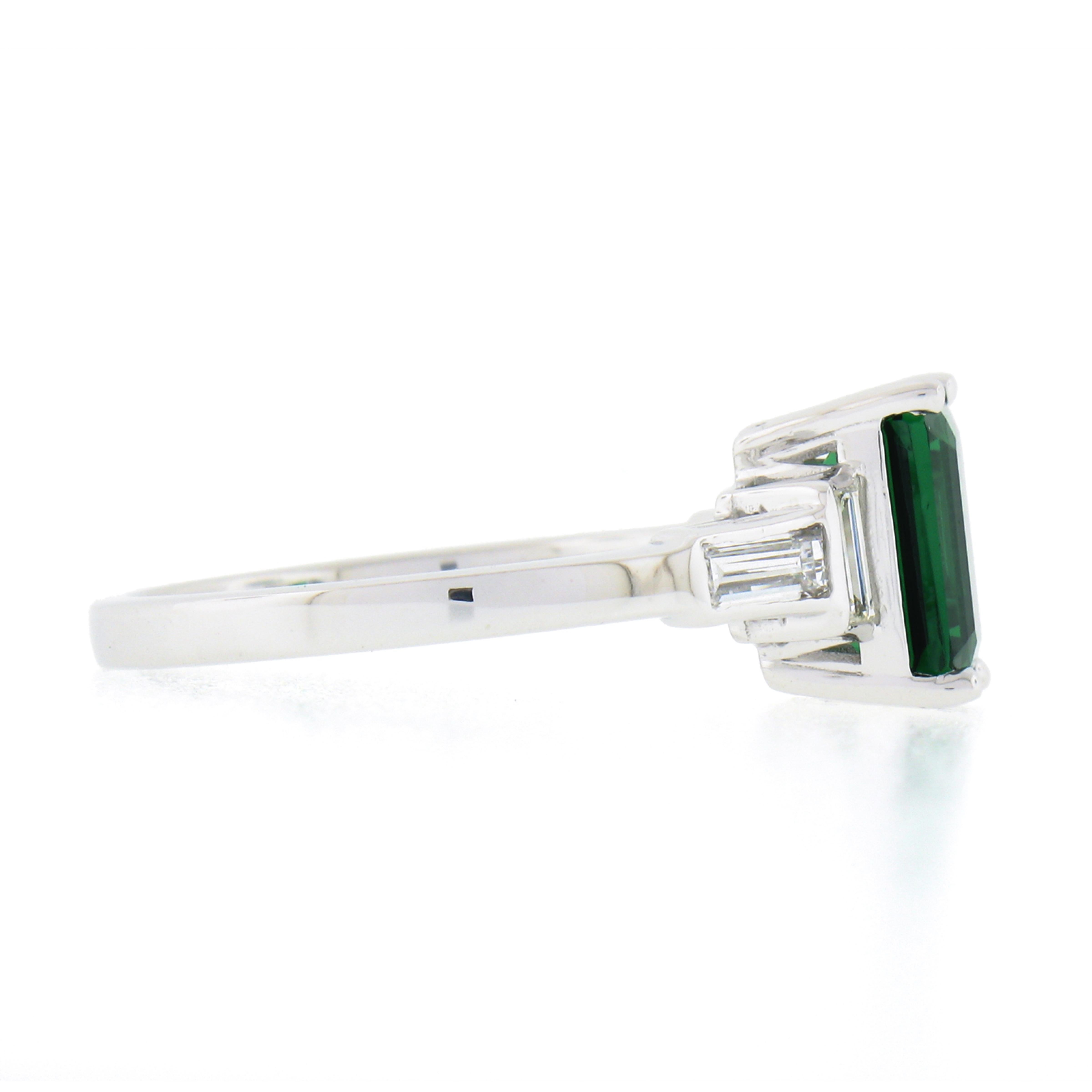 Here we have a fancy, and truly magnificent green tsavorite and diamond ring newly crafted in solid platinum. The ring features a natural, GIA certified, elongated emerald step cut green tsavorite that weighs exactly 2.03 carats and is neatly prong
