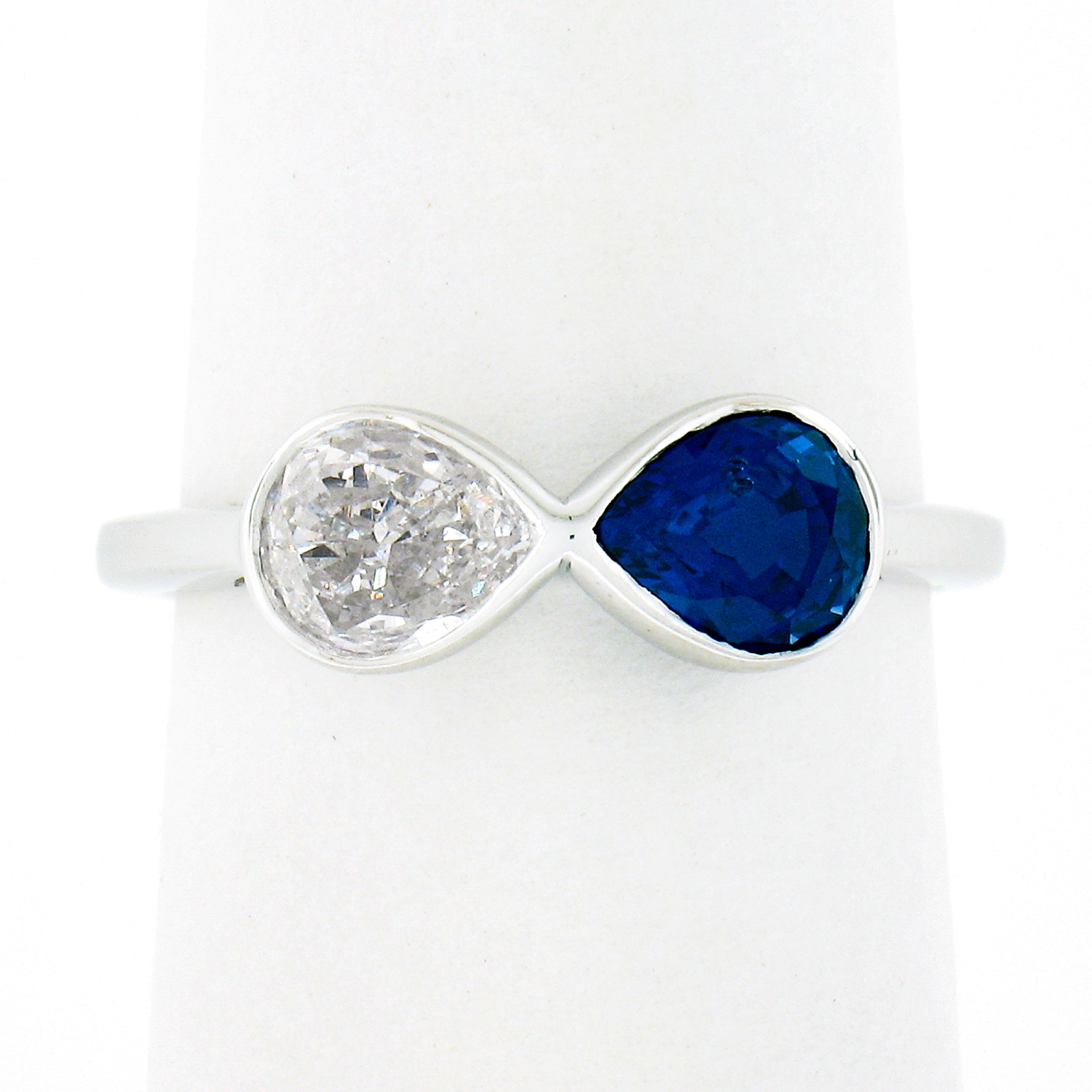 This magnificent, custom made, sapphire and diamond two stone ring is newly crafted in solid platinum. It features a truly breathtaking, GIA certified, pear cut sapphire, neatly bezel set at one side at the top of the ring with a pear cut diamond
