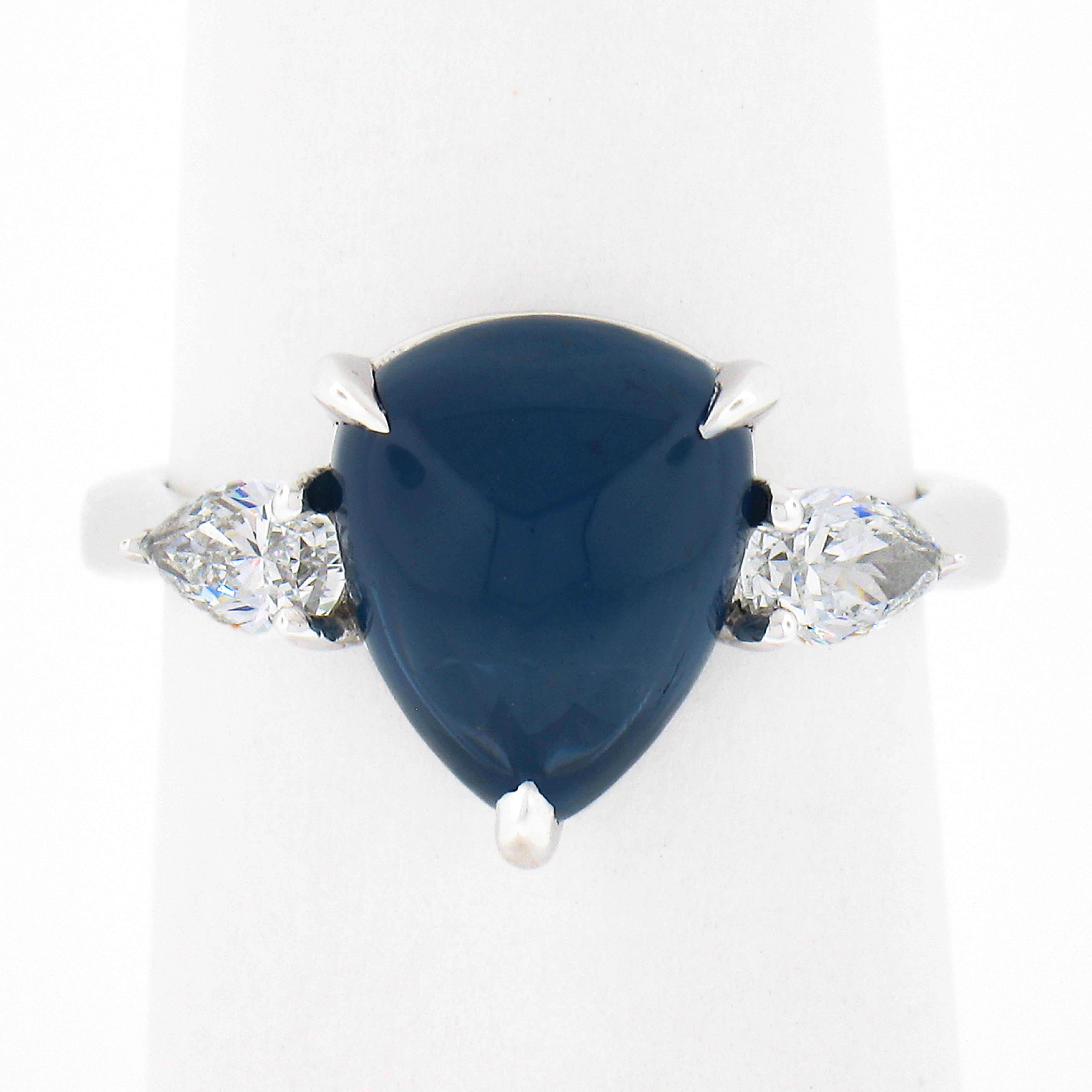 This uniquely designed and very well made three-stone ring is newly crafted in solid platinum and features a magnificent, Gubelin certified, natural sapphire stone perfectly claw-prong set at its center. The modified triangle cabochon cut sapphire