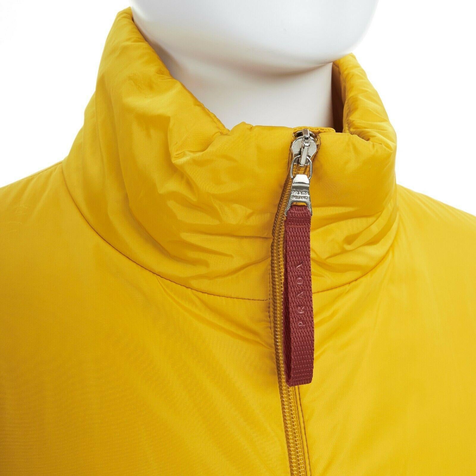new PRADA Red Line yellow polyester padded long length snowboard jacket IT46 S
PRADA RED LINE
100% nylon. 100% polyester padding. Yellow. 
Stand collar. Zip front closure. Signature Red line nylon zipper pull. 
Long sleeves. Elasticated dual layered