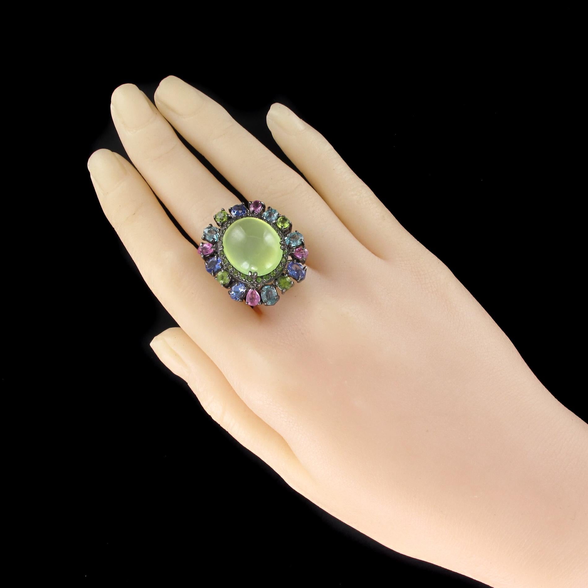 Ring in silver, partially black rhodium-plated on the plate.
Sumptuous gemstone ring, the setting is set in the center with 4 x 2 claws of a prehnite cabochon surrounded by peridots and a set of precious stones offset claws set to give a beautiful