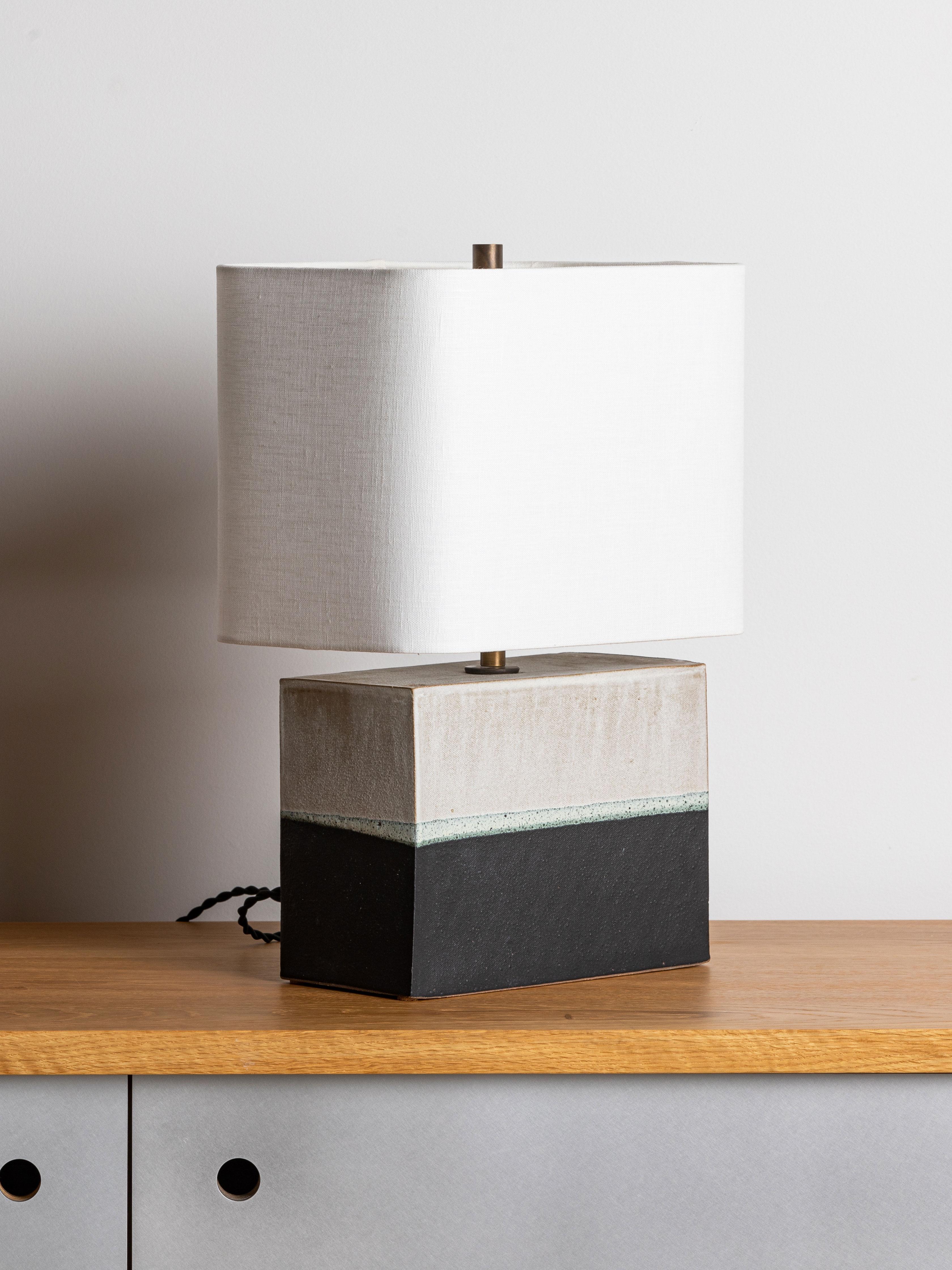 Our stoneware New Preston Lamp is handcrafted using slab-construction techniques.

Finish

- Dipped glaze, pictured in parchment & matte-black 
- Antique brass fittings
- Twisted black-cloth cord
- Full-range dimmer socket
- Rectangular round-corner