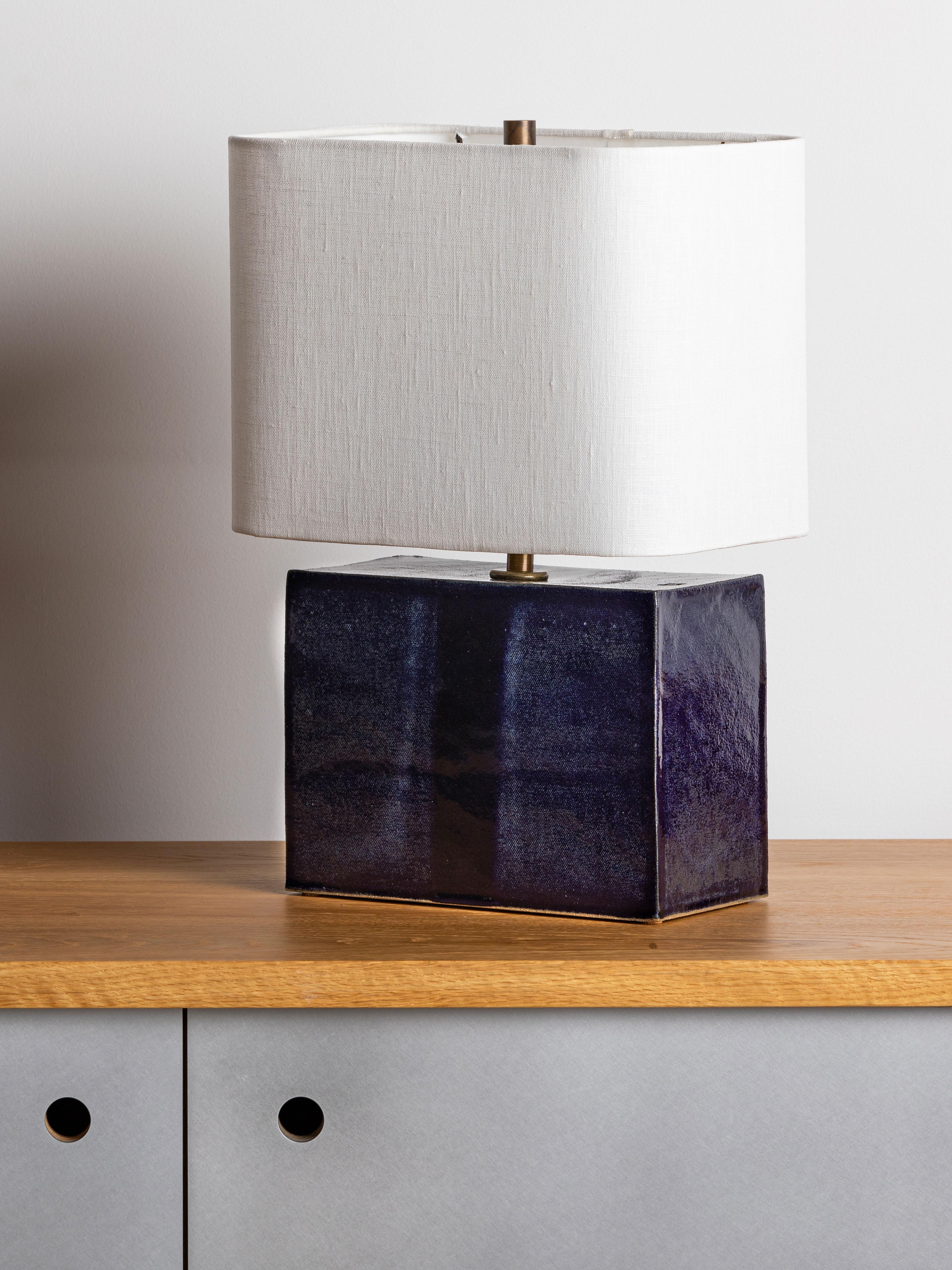 Our stoneware New Preston lamp is handcrafted using slab-construction techniques.

Finish

- Dipped glaze, pictured in navy 
- Antique brass fittings
- Twisted black-cloth cord
- Full-range dimmer socket
- Rectangular round-corner linen
