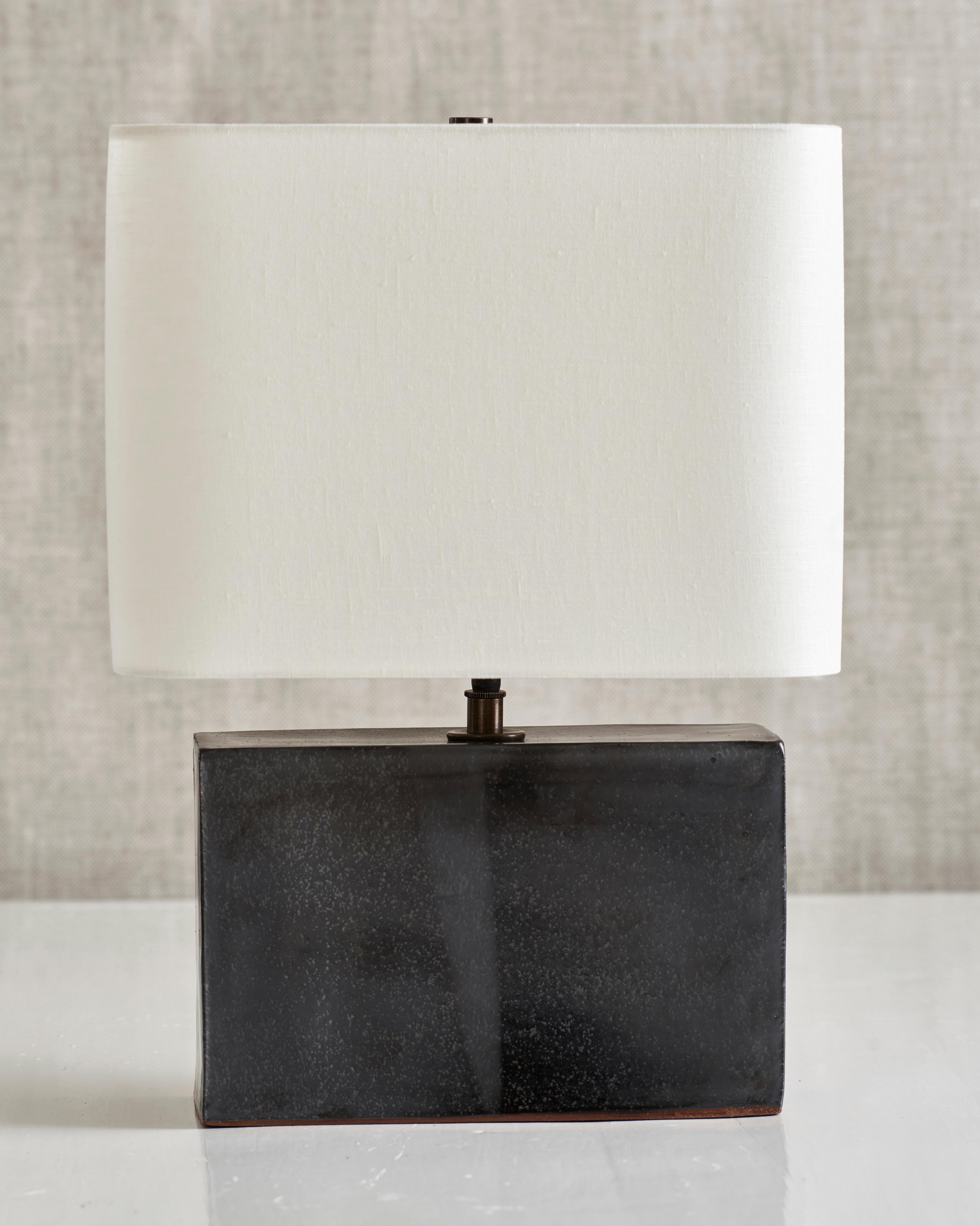 Handmade stoneware slab construction. Lamps are individually crafted and one of a kind.

Lead glaze. Antique brass fittings with braided black silk cord and off-white linen shade.

Box height 6.5”
Box width 10”
Box depth 3.75”
Shade width 12”