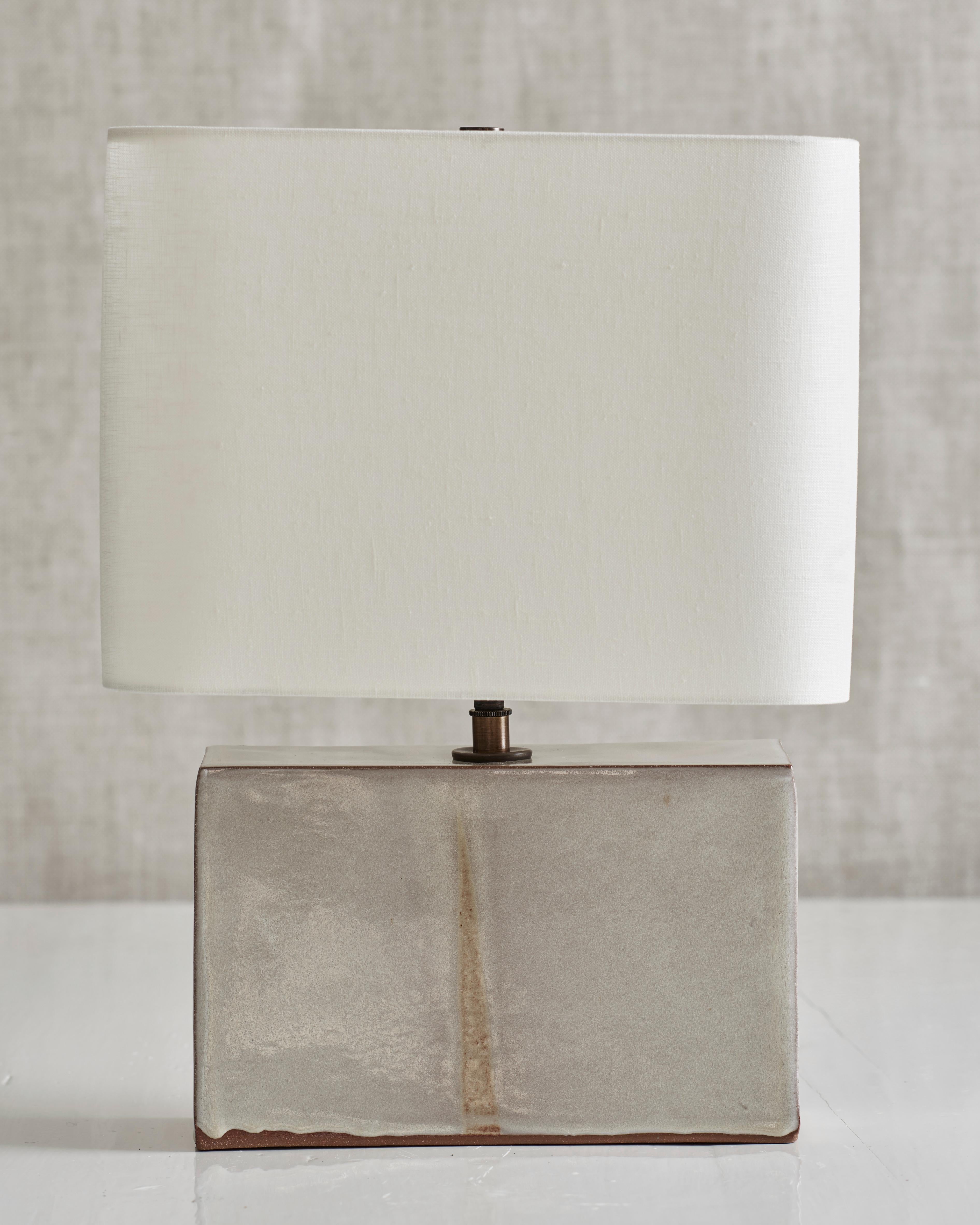 Handmade stoneware slab construction. Lamps are individually crafted and one of a kind.

White glaze. Antique brass fittings with braided black silk cord and off-white linen shade.

Measures: Box height 6.5”
Box width 10”
Box depth