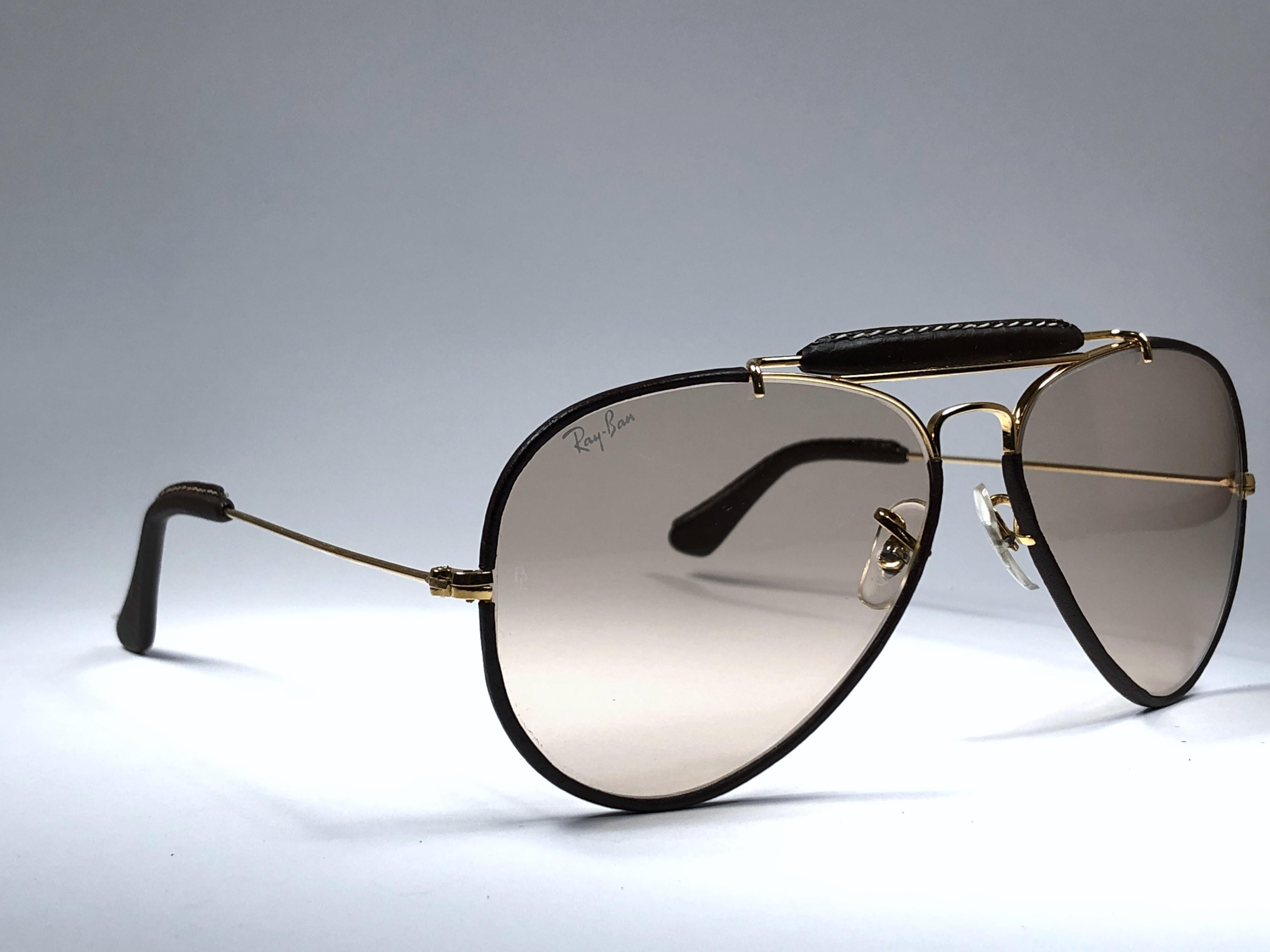 Ray Ban Outdoorsman 58 mm brown Leather with changeable brown lenses with golden Ray Ban logo. The left lens has a minor flaw other than that perfection! B&L etched in the lenses, So mid 1970's. 
Original Ray Ban B&L case with light sign of wear due