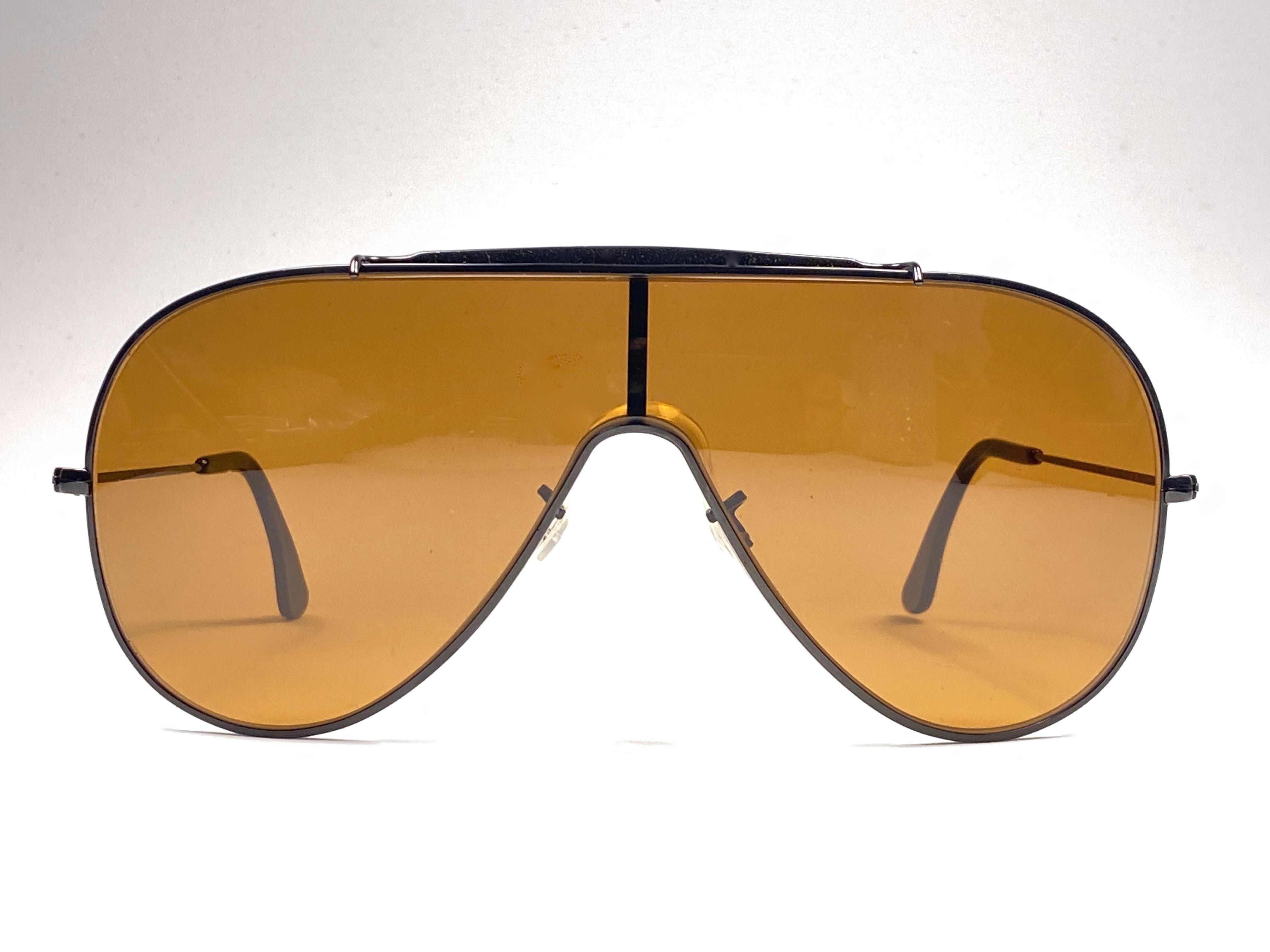Ray Ban Wings black with amber mono lenses.  
Please notice that this item is nearly 40 years old and show   wear on the mono lens in the shape of light scratches.

Made in Usa.

FRONT : 15 CMS  
LENS HEIGHT : 6 CMS  
LENS WIDTH : 15 CMS
