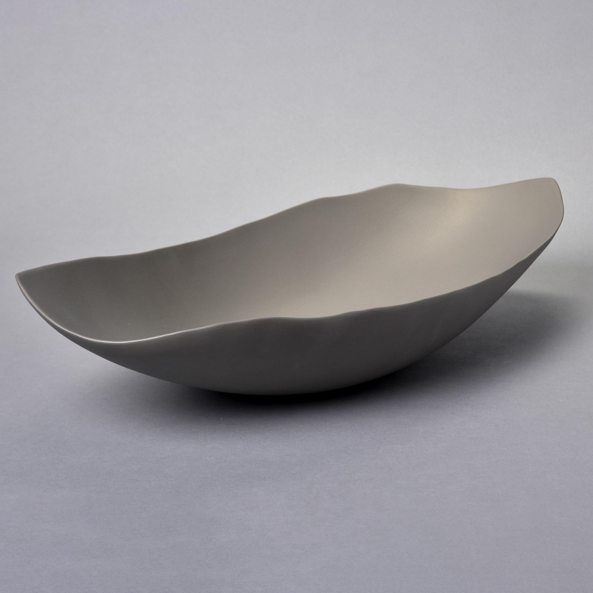 Nuova ciotola in studio Pottery di Rina Menardi. La ciotola Barchetta è una ciotola centrale allungata e poco profonda con un bordo irregolare. Forma scultorea dalle pareti sottili, smaltata in bronzo con finitura opaca di colore grigio medio. Un