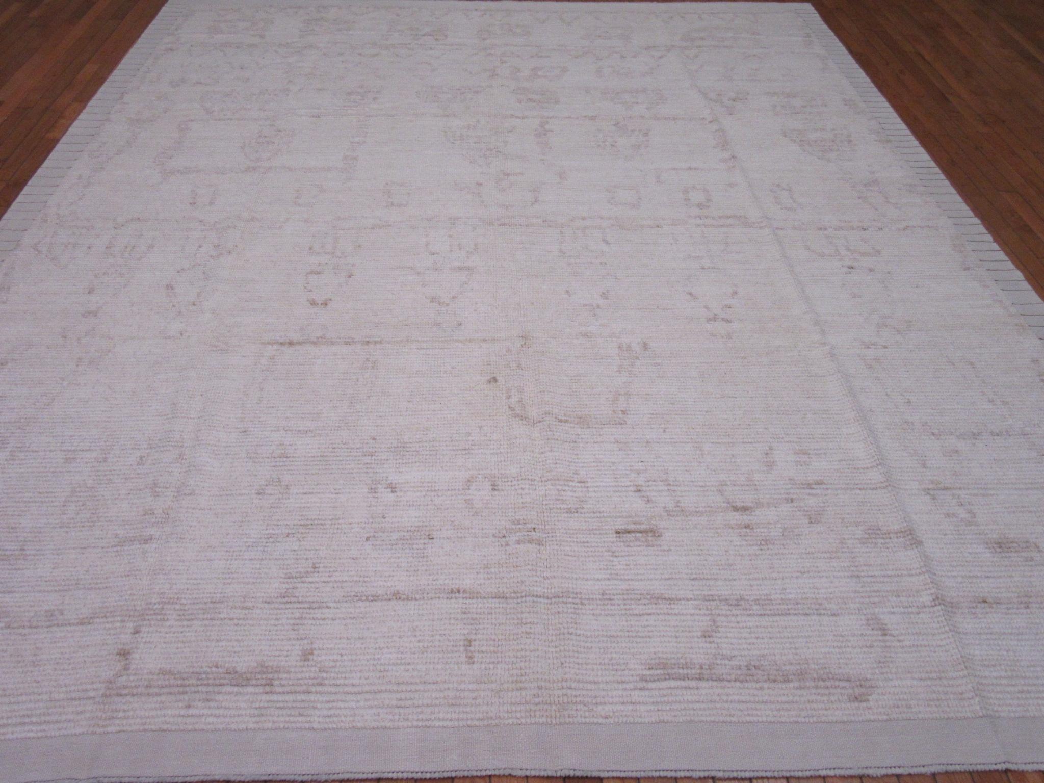 This is a new hand knotted Tulu rug made with good quality wool from Turkey. It has a fluffy long hair pile common with these types of rugs. It has a tribal design in soft mocha colors on an ivory background. It measures 9' 4'' x 12' 9''.