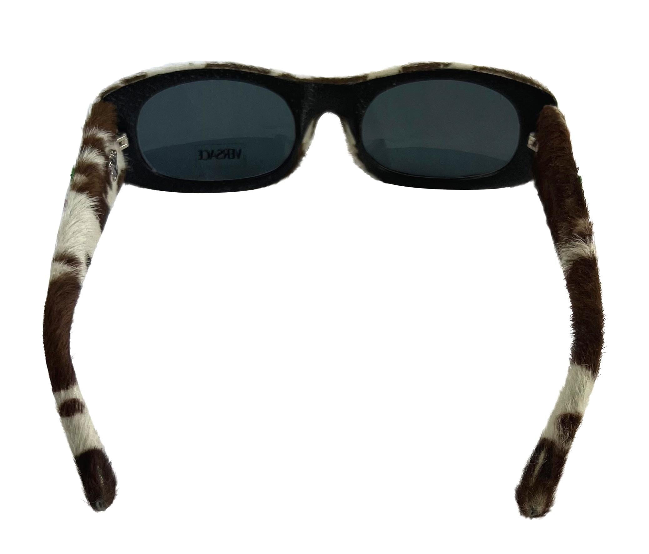 Presenting a fabulous pair of cow-print pony hair Versace sunglasses, designed by Donatella Versace. From the Spring/Summer 1999 collection, these sunglasses are covered in dotted pony hair and feature purple and green pom-pom details at the