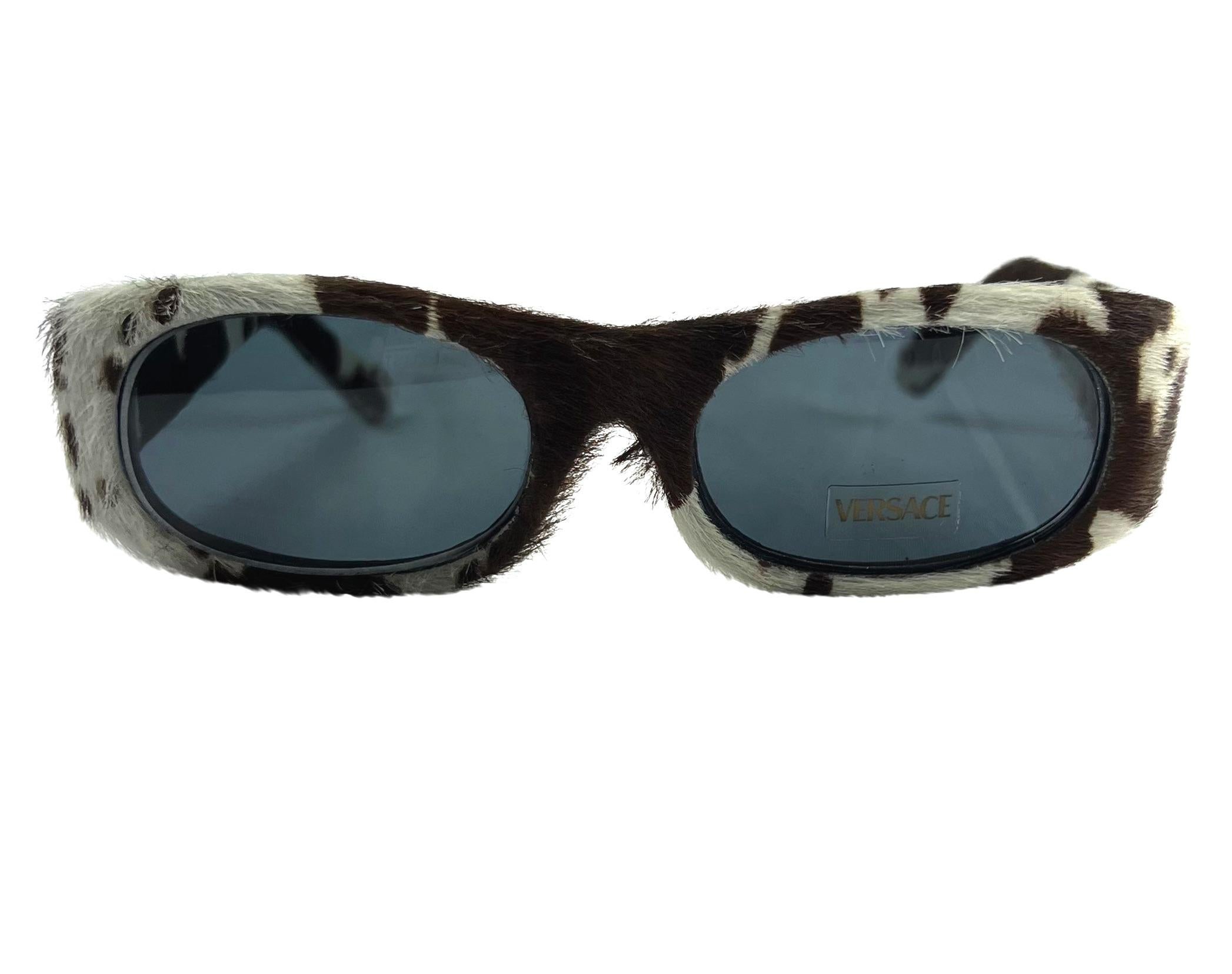 TheRealList presents: a fabulous pair of cow-print pony hair Versace sunglasses, designed by Donatella Versace. From the Spring/Summer 1999 collection, these sunglasses are covered in dotted pony hair and feature purple and green floral details at