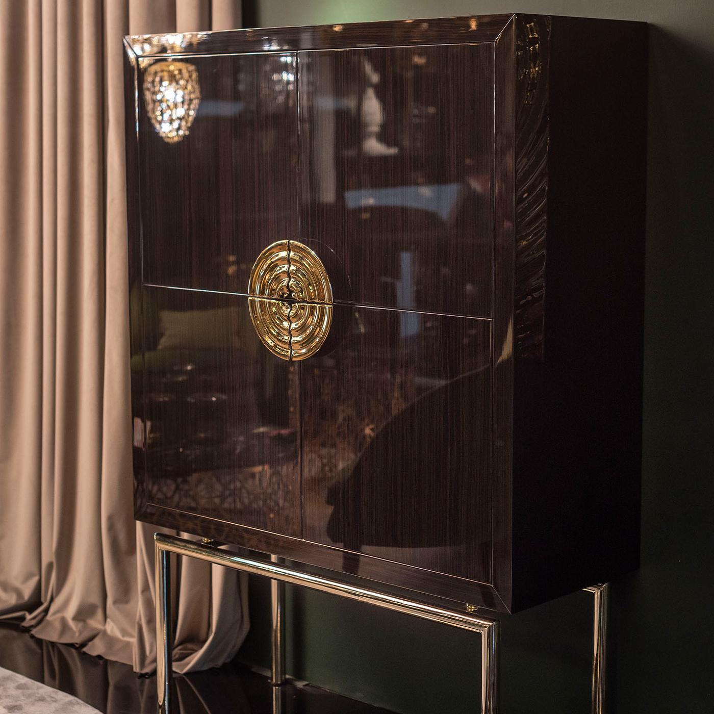 Part of the New Secret Collection, this modern 4-door cabinet offers unparalleled sophistication. Raised on a tubular metal base with a precious 24k-gold finish, the honeycomb ebony has an alluring brushed 100 Gloss finish that enhances the