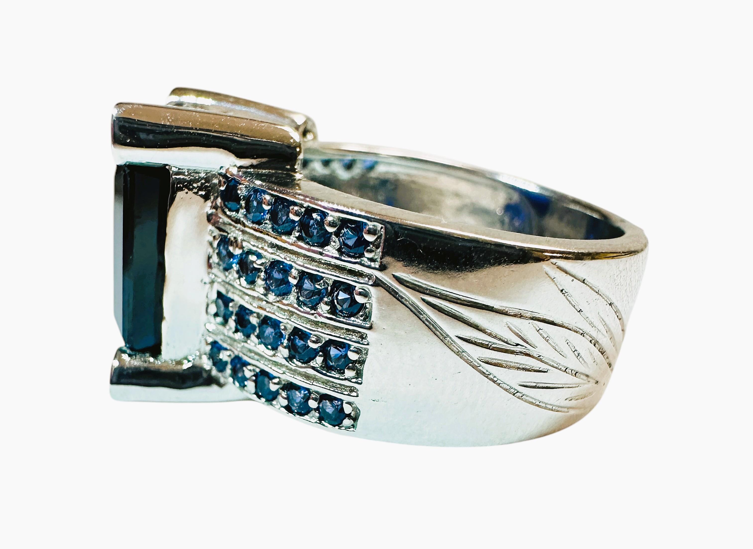 The stone is from Sri Lanka and is just exquisite. The stone is a royal blue sapphire and is 10.02 cts.  It is an emerald cut stone and measures 12 x 10 mm and has 4 rows of diamond cut blue sapphires running down each side of the band.  The 