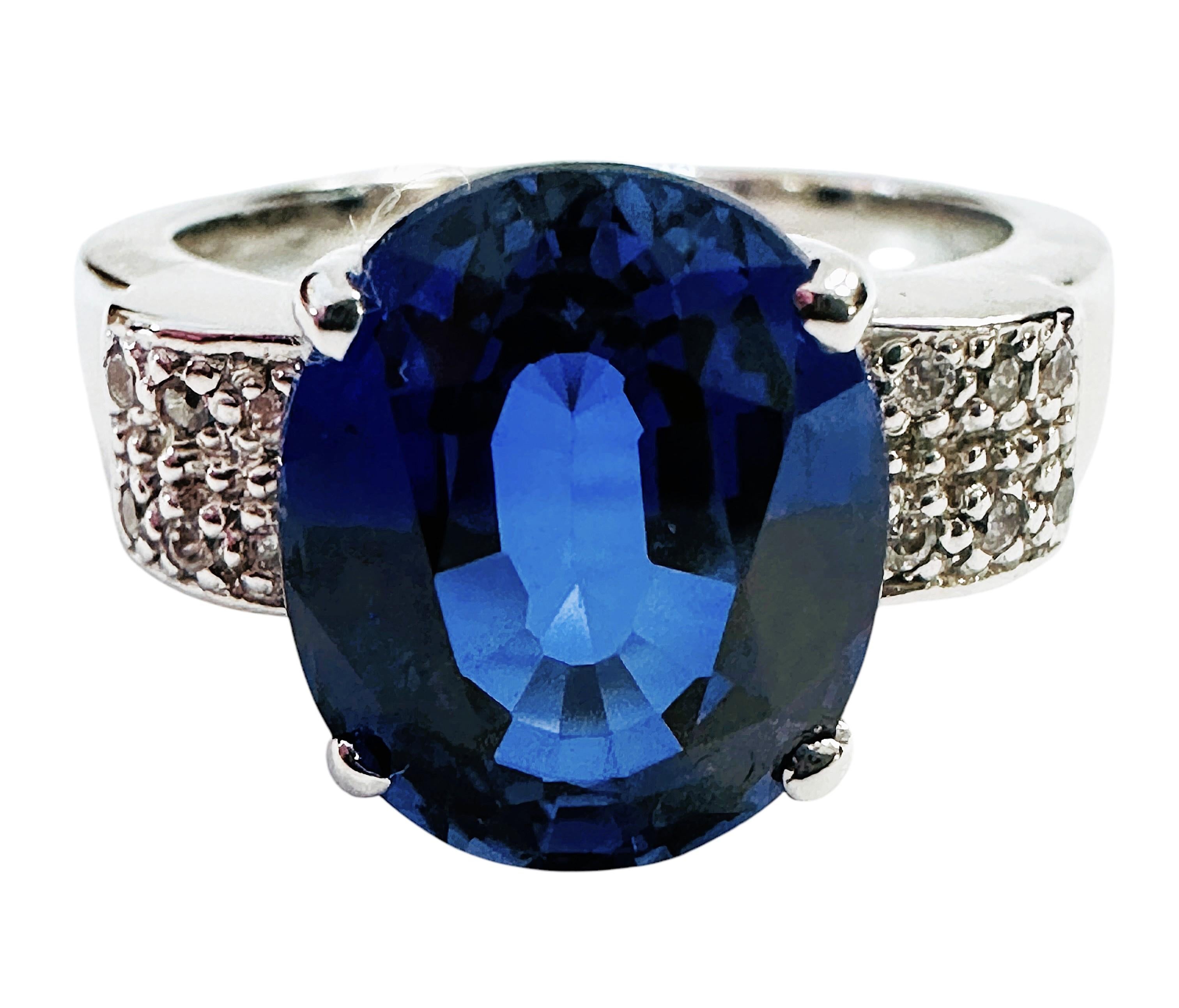 La piedra procede de Sri Lanka y es simplemente exquisita. La piedra es un zafiro azul de 6.75 quilates.  Es una piedra de talla ovalada, mide 12 x 9,8 mm y está flanqueada por zafiros blancos de talla diamante en la banda.  El anillo es de la talla