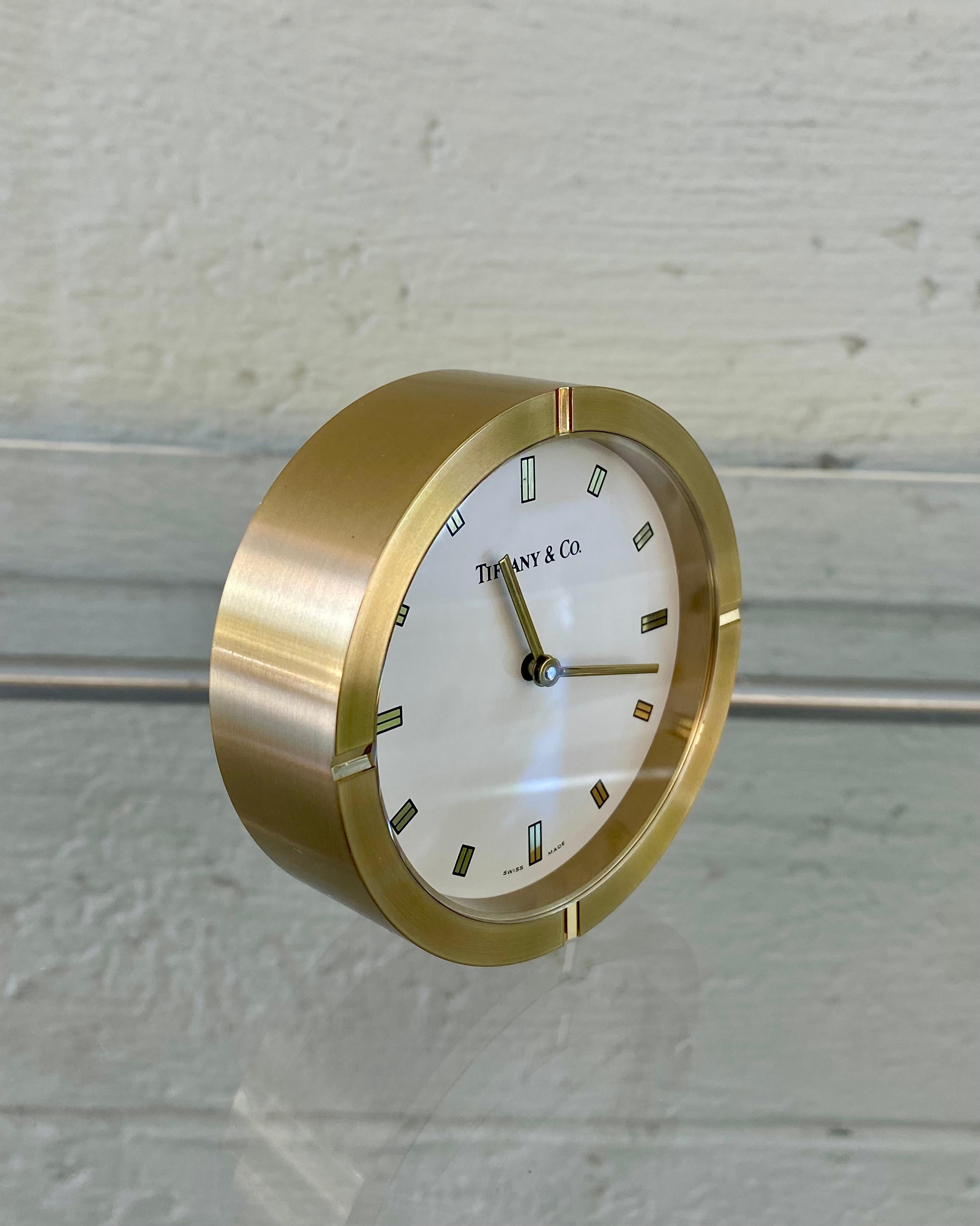 Tiffany & Co. brass round desk clock. Swiss made with quartz resonator. Measures 3 inches around.  Classic and timeless design only by Tiffany. Back cover removed the movement is hallmarked Tiffany & Co. Swiss Made Quartz. Comes with box and dustbag.