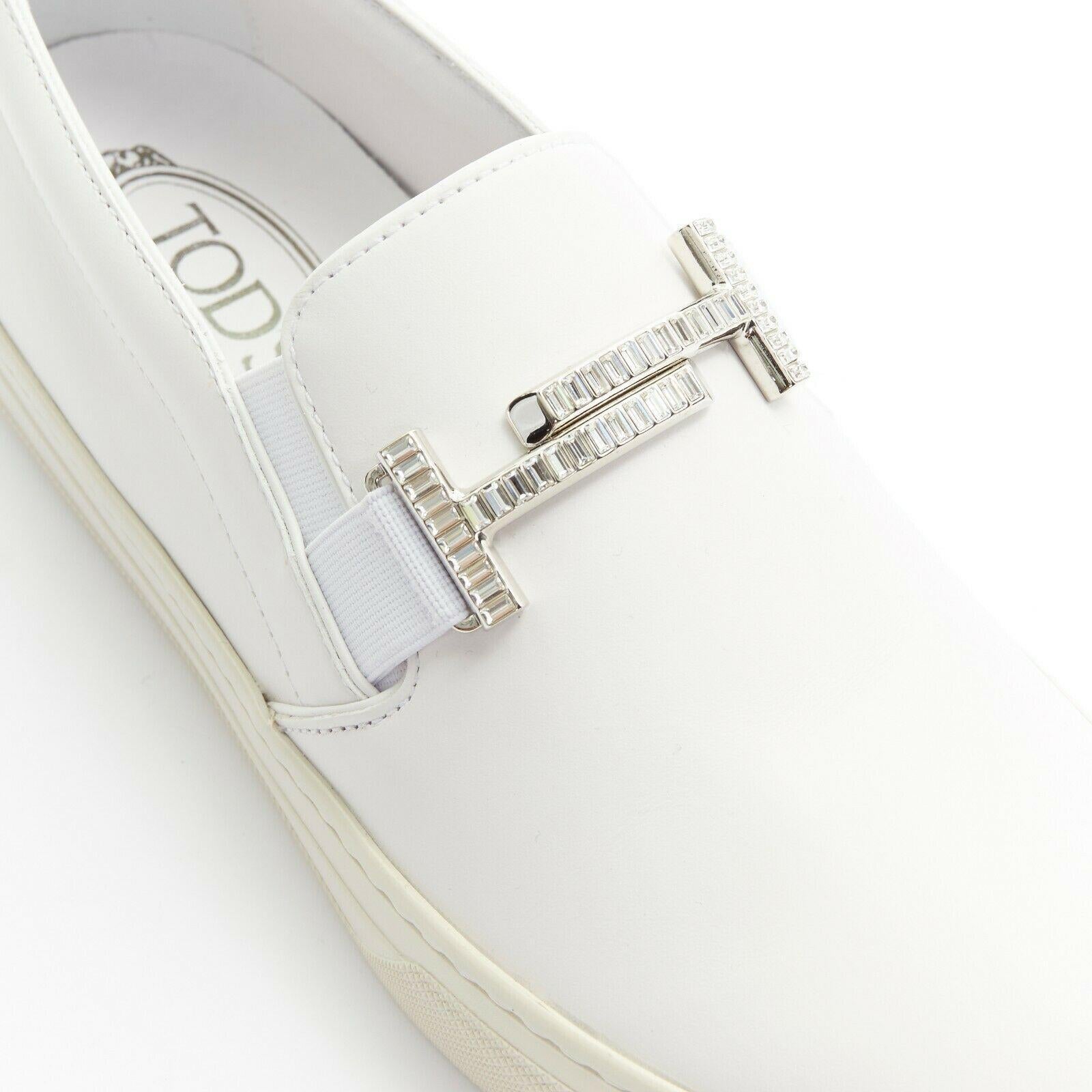 new TOD'S white leather crystal paved buckle round toe sneaker skate shoe EU37.5
TOD'S
White leather upper. 
Silver-tone metal buckle. 
Clear rectangular crystal pave. 
Elasticated stretch inset. 
Tonal stitching. Round toe. 
White outsole. 
Tod's