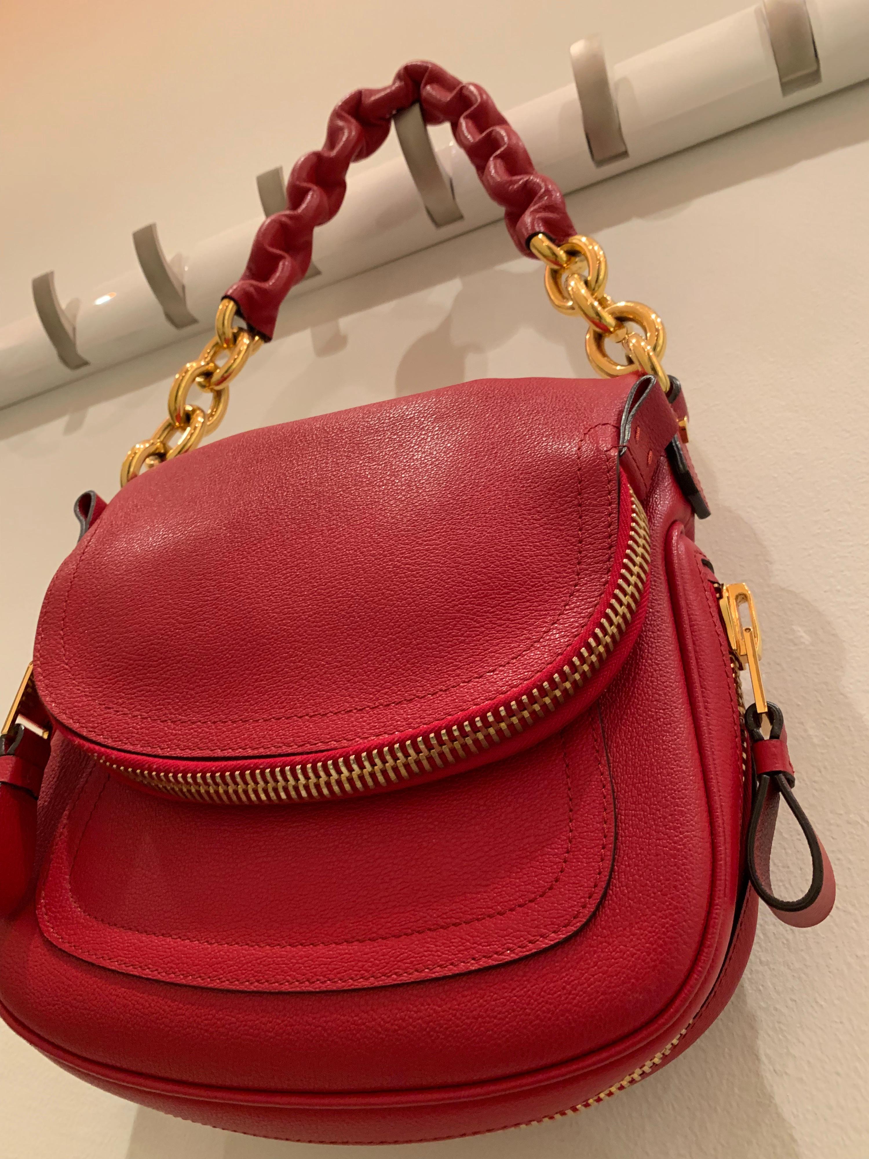 A fabulous new-never used Tom Ford crimson textured leather saddlebag-styled shoulder bag with heavy gold chain handle.  Handle at grip has leather molded around chain for comfort.  Saddle flap is a zippered pocket.  Originally purchased at Bergdorf
