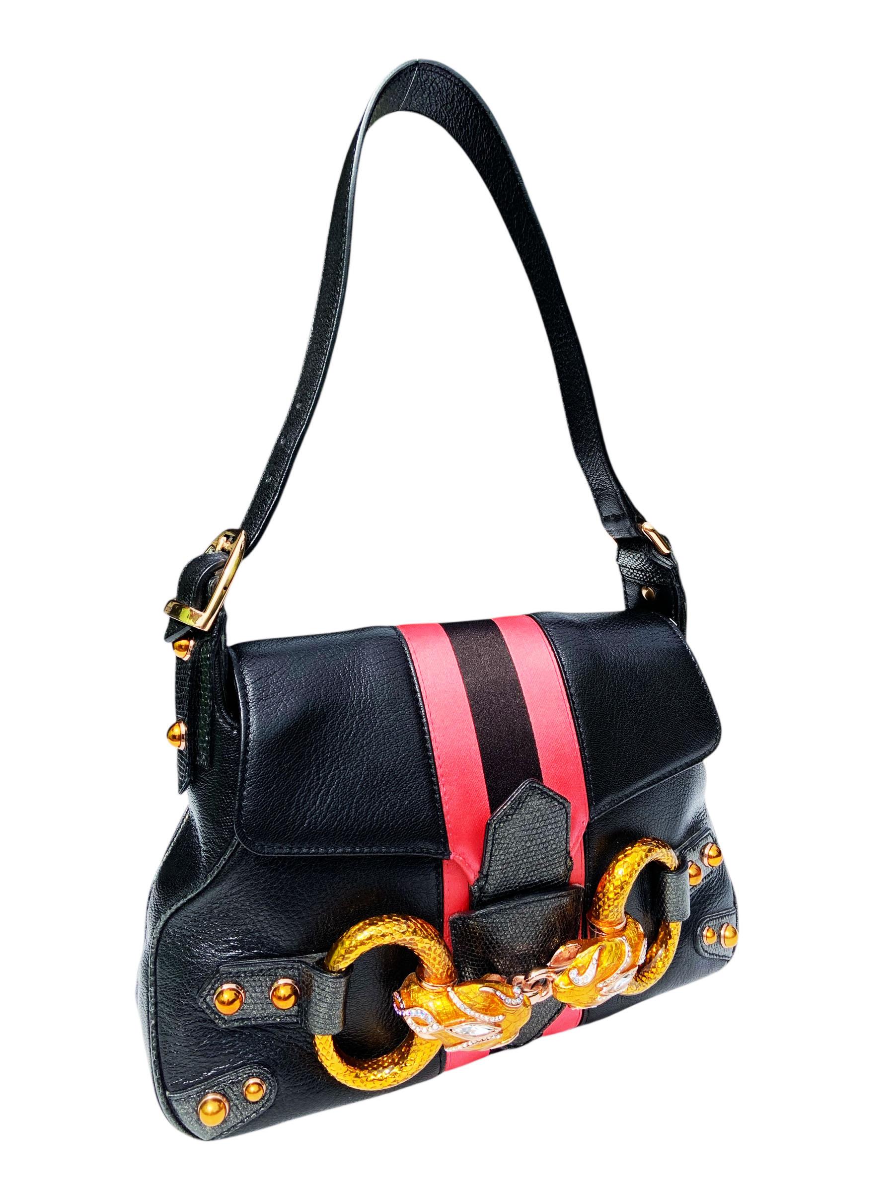 
An iconic and rare collector’s piece from Tom Ford’s final years at Gucci, this Fall 2004 limited edition shoulder bag is a masterclass in bold luxury and statement design. Crafted from supple black leather with tonal lizard leather detailing, the