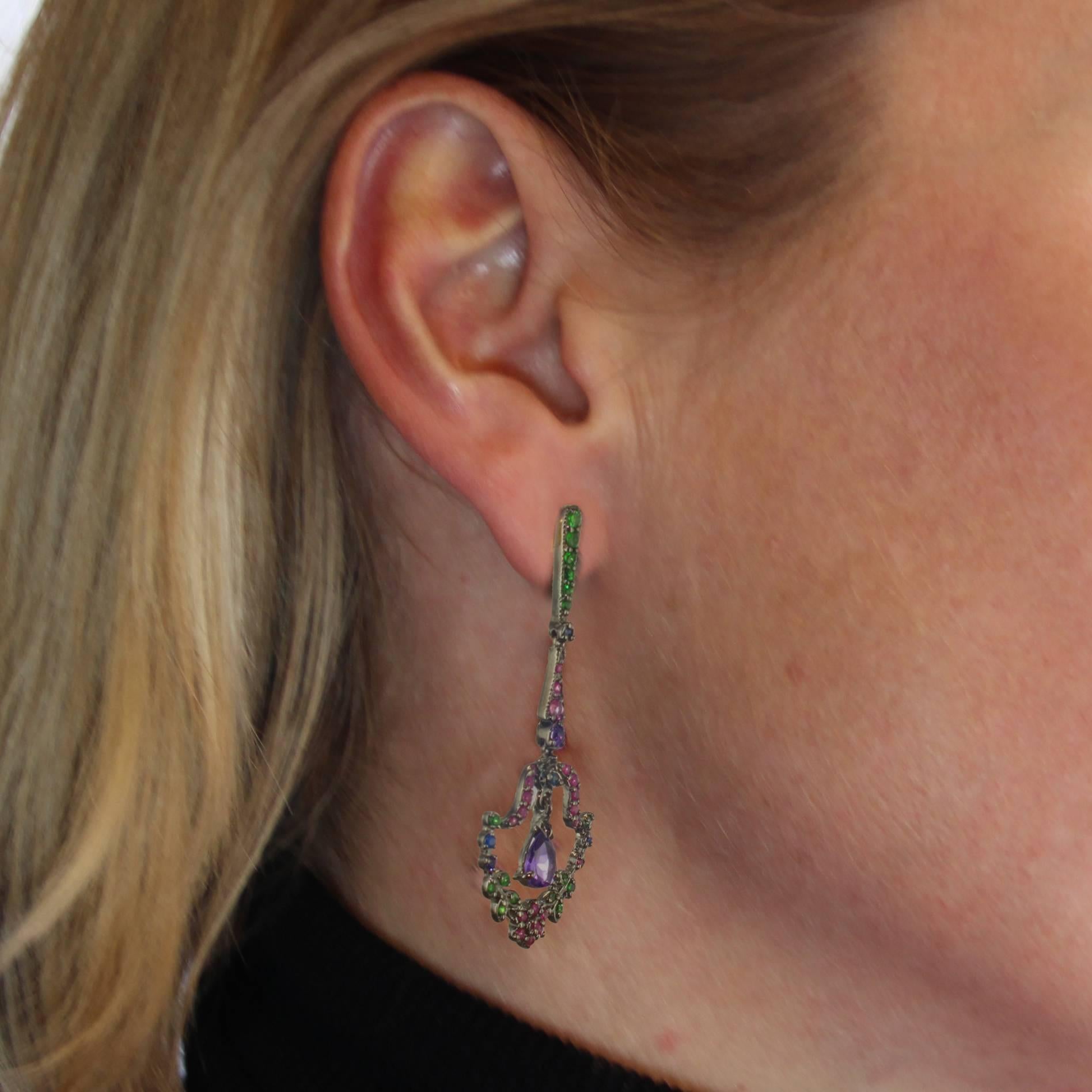 For pierced ears.
Earrings in silver with black rhodium and 18 carats yellow gold, for the stems and the clasps.
These lovely earrings are made of a line of tsavorite garnets that holds a line of pink sapphires, itself holding a lantern-shaped