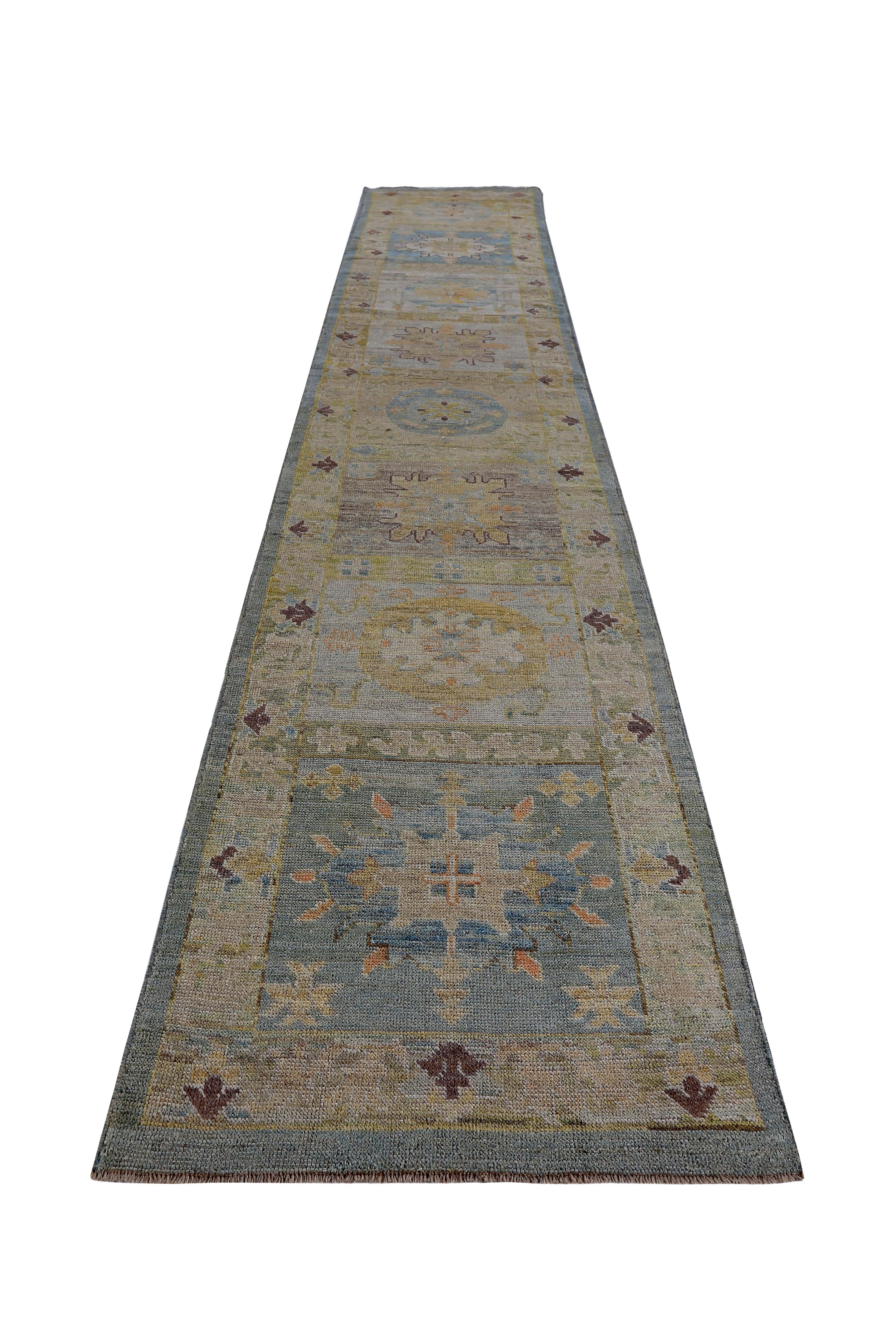 New Turkish runner rug made of handwoven sheep’s wool of the finest quality. It’s colored with organic vegetable dyes that are certified safe for humans and pets alike. It features floral details in blue, yellow and green over a brown field. Flower