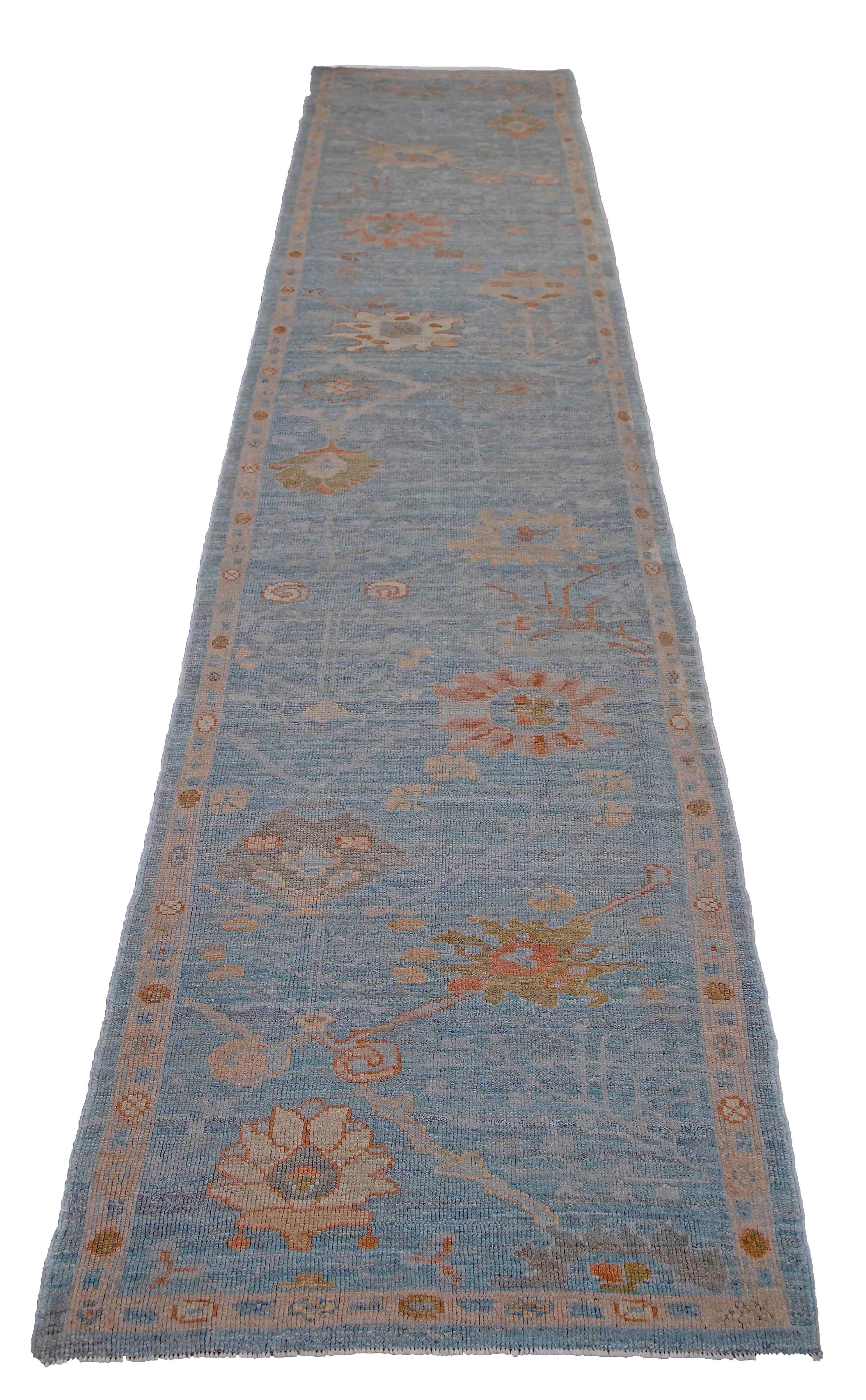 New Turkish runner rug made of handwoven sheep’s wool of the finest quality. It’s colored with organic vegetable dyes that are certified safe for humans and pets alike. It features floral details in green and pink over a lovely blue field. Flower