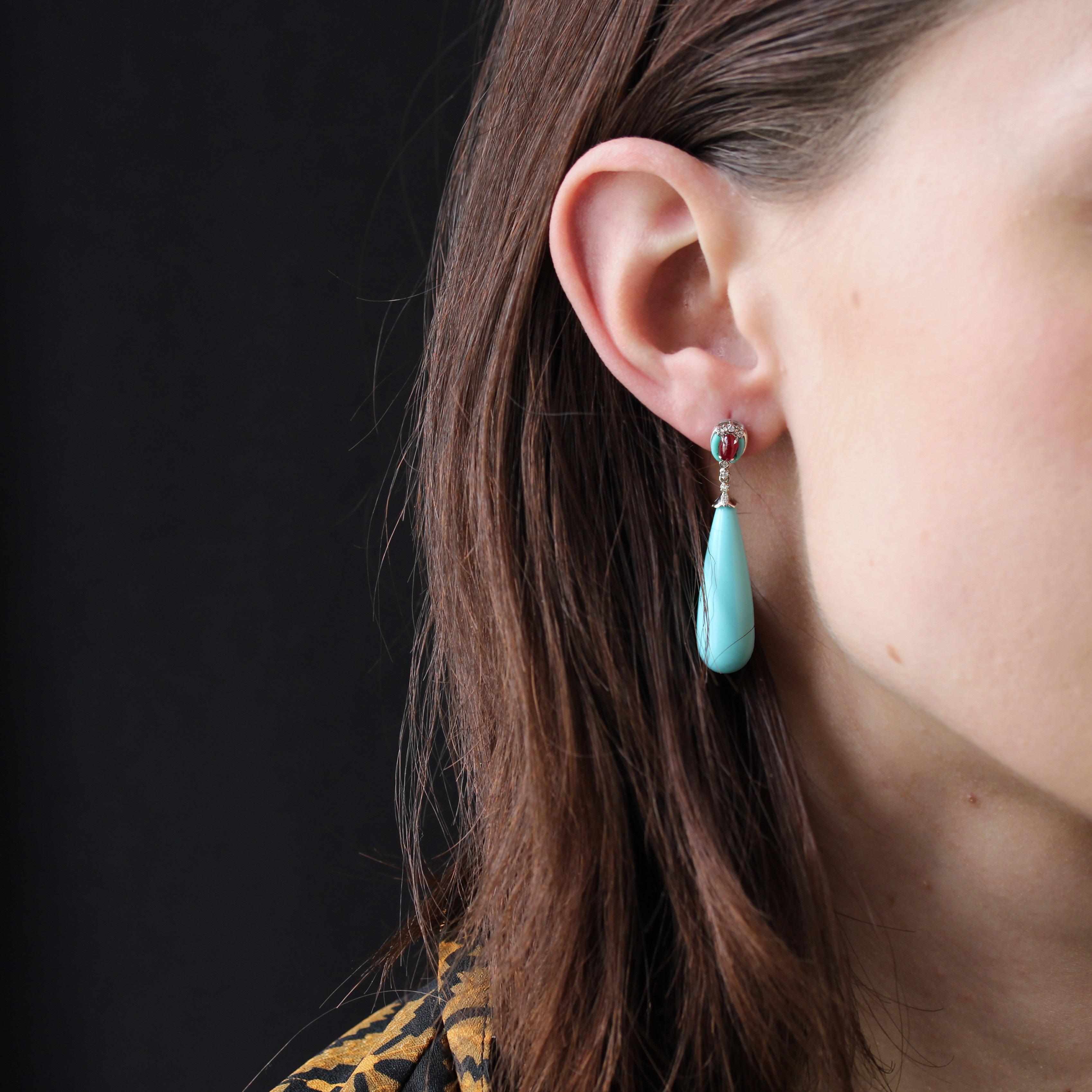 For pierced ears.
Earrings in 18 karat white gold.
Long and slender, these earrings feature an oval motif set in the center with a ruby cabochon flanked on either side by 2 half-moon-cut turquoise stones. Four modern brilliant-cut diamonds also