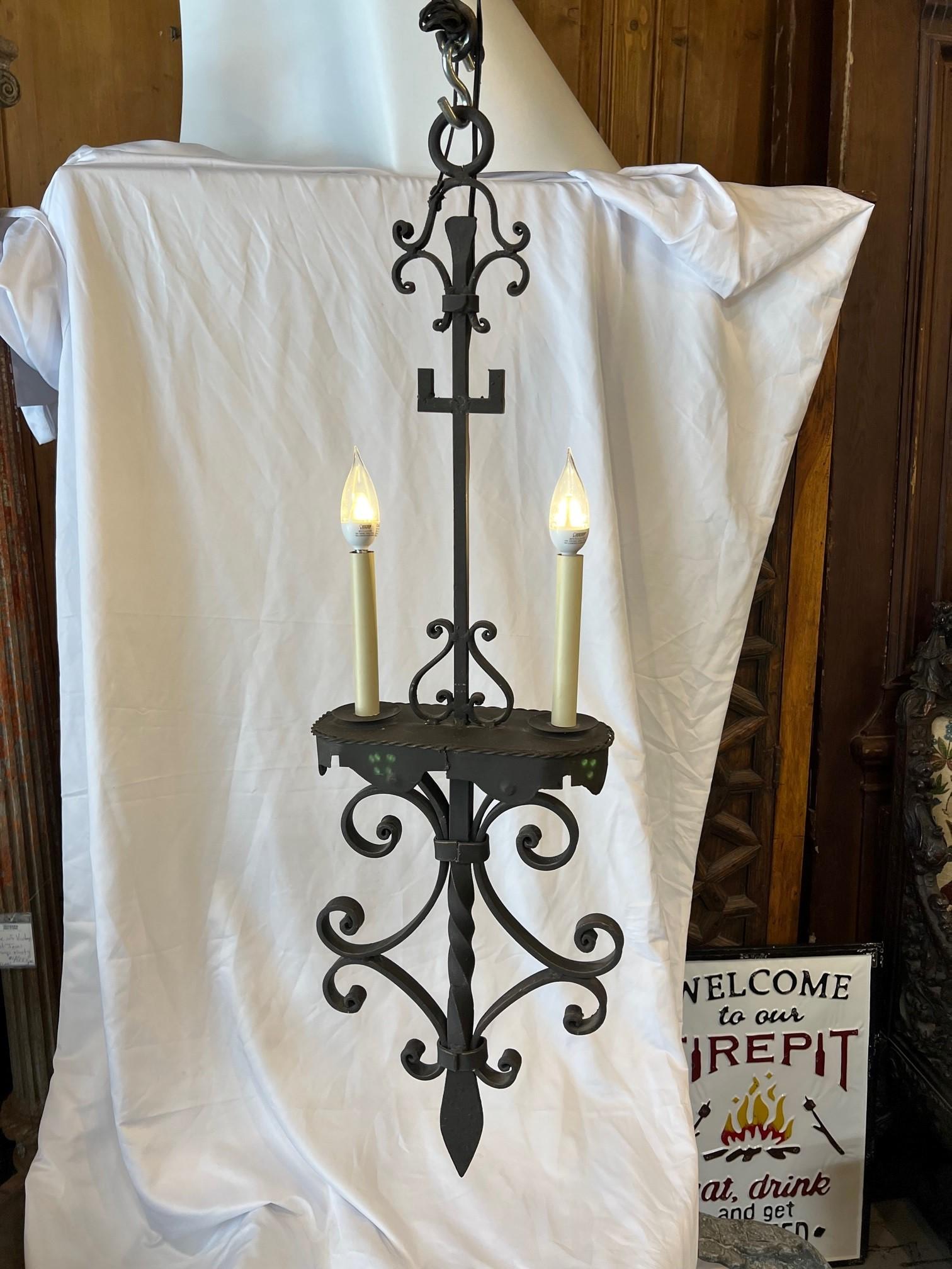 Luminaire suspendu en fer forgé forgé à la main avec un travail de rouleau de fer et un centre de torsion rainuré martelé à la main avec deux lumières. Il s'agit d'une jolie lampe forgée à la main qui serait parfaite au-dessus d'un îlot de cuisine