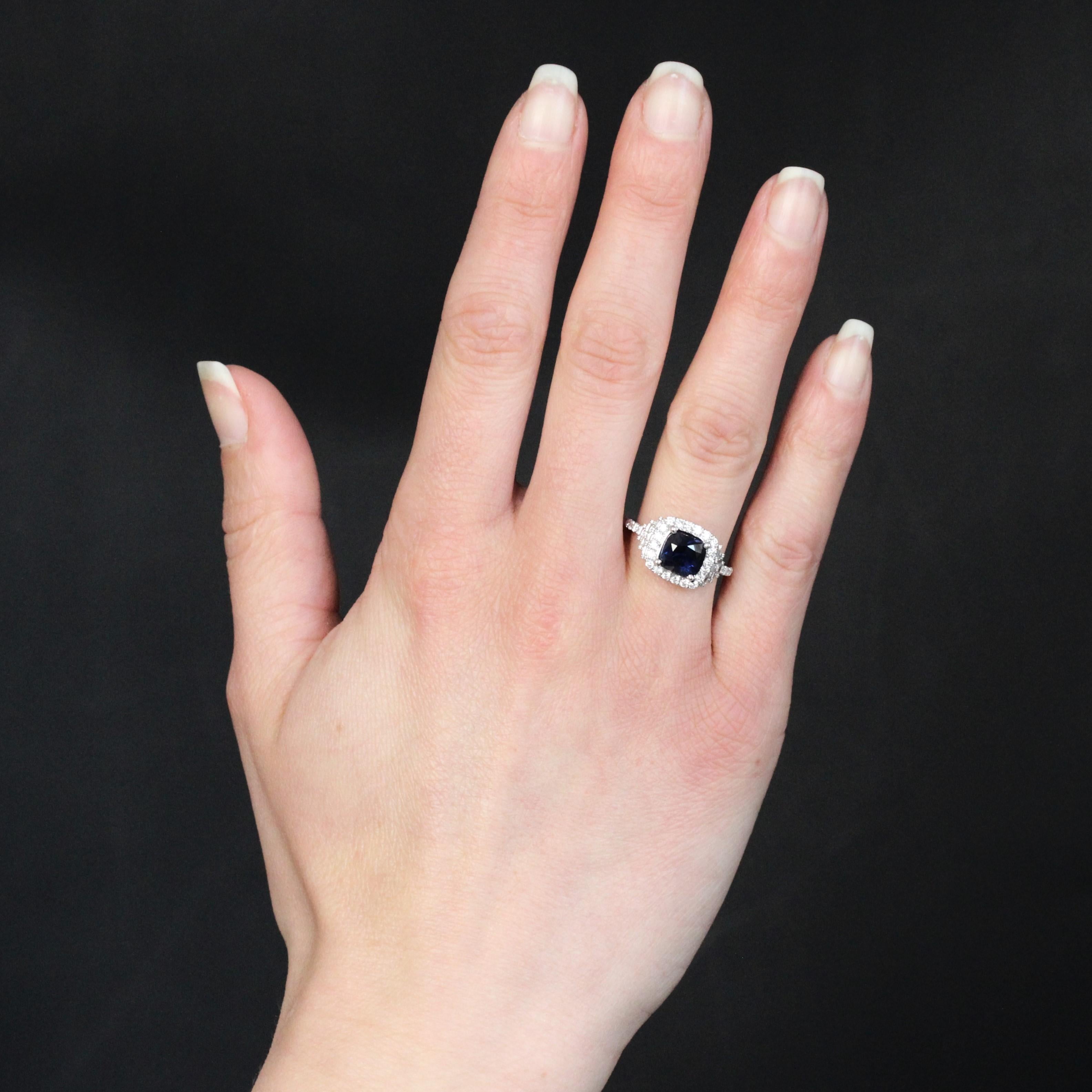 Anello in oro bianco 18 carati, marchio di fabbrica con testa d'aquila.
Questo anello in oro bianco forma un cuscino interamente incastonato di moderni diamanti a taglio brillante e ornato al centro da uno zaffiro della stessa forma, tenuto in