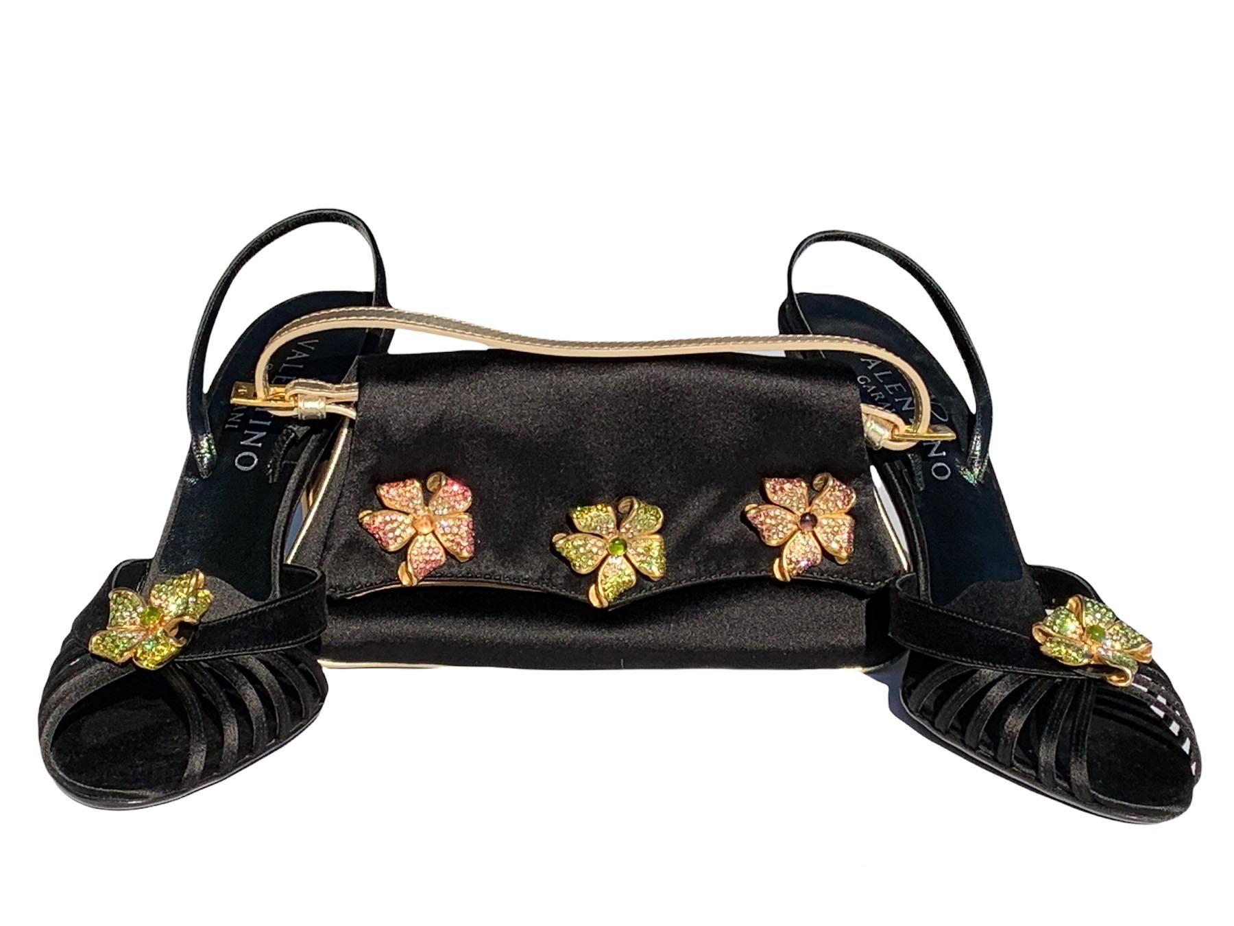 New Valentino Garavani Black Jeweled Slingback Sandals with Matching Clutch
2006 Collection
Black Satin Sandals Finished with Gold Tone Metal Flower Full of Green Crystals, Heel Height - 4 inches.
Black Satin Matching Clutch Finished with Gold Tone