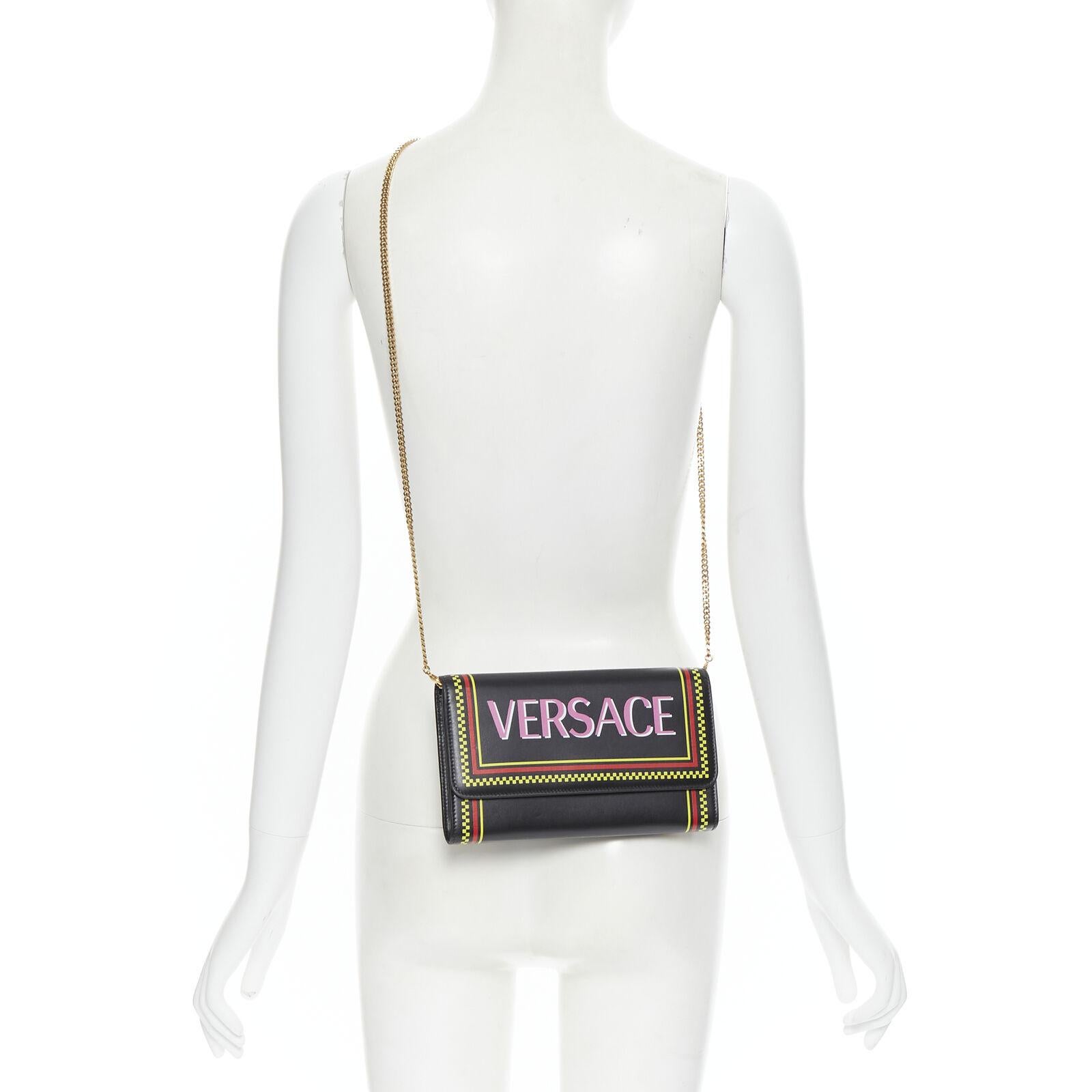 new VERSACE 90s pink logo black leather WOC flap clutch crossbody bag 
Reference: TGAS/B00506 
Brand: Versace 
Designer: Donatella Versace 
Model: 90's logo wallet on chain clutch 
Material: Leather 
Color: Black 
Pattern: Solid 
Closure: Button