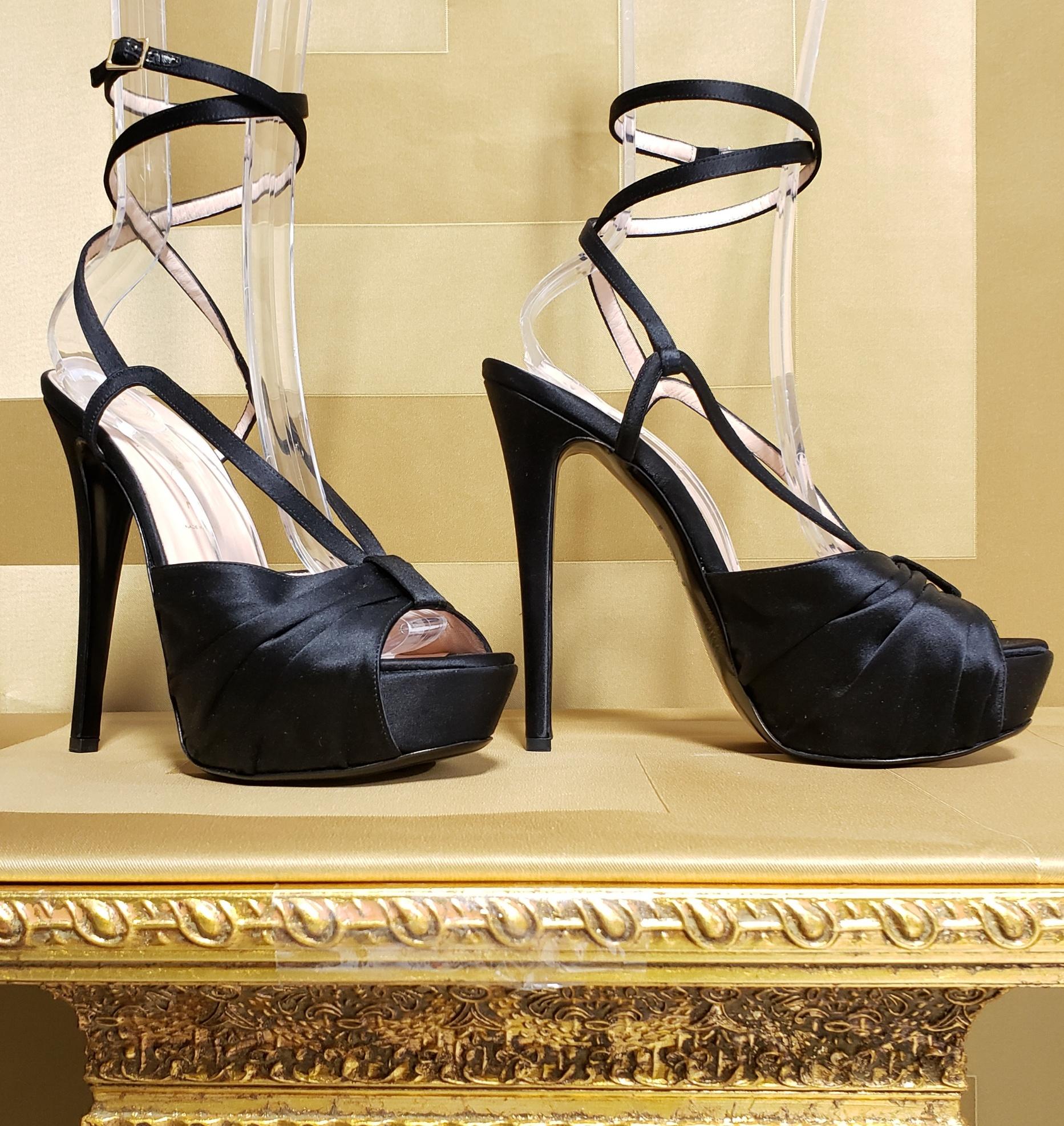 VERSACE
New sandal reaches new heights of show-stopping style in black satin with sexy platform.
 Strap around the leg.

    Color: BLACK
leather lining

 Heel measures  6''
Platform is about 1 1/2