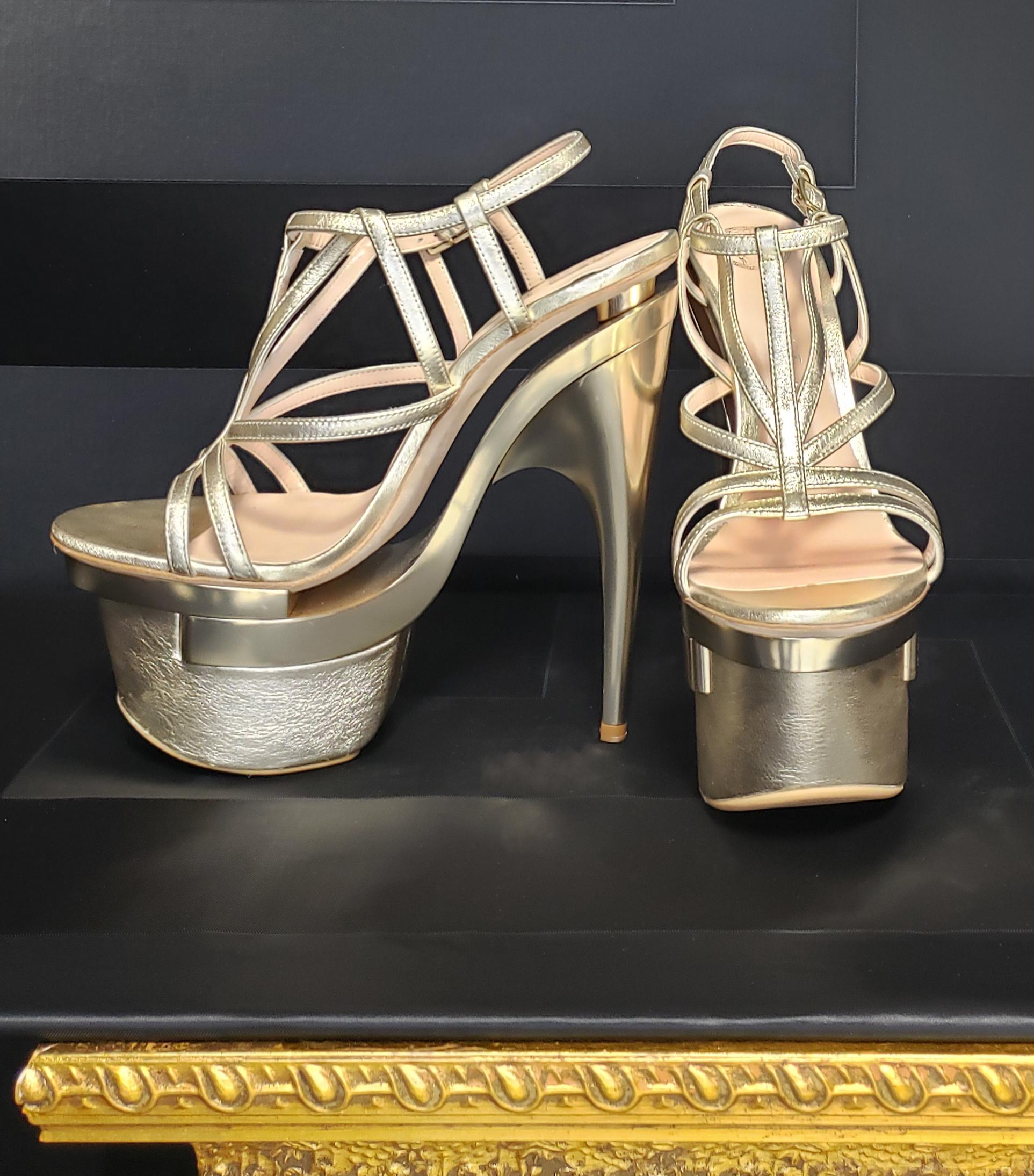 VERSACE
New sandal reaches new heights of show-stopping style in gold metallic leather with sexy platform. 
    Color: GOLD 
Content: 100% Leather
Leather lining
 Heel measures  7''
Platform is about 2 1/2