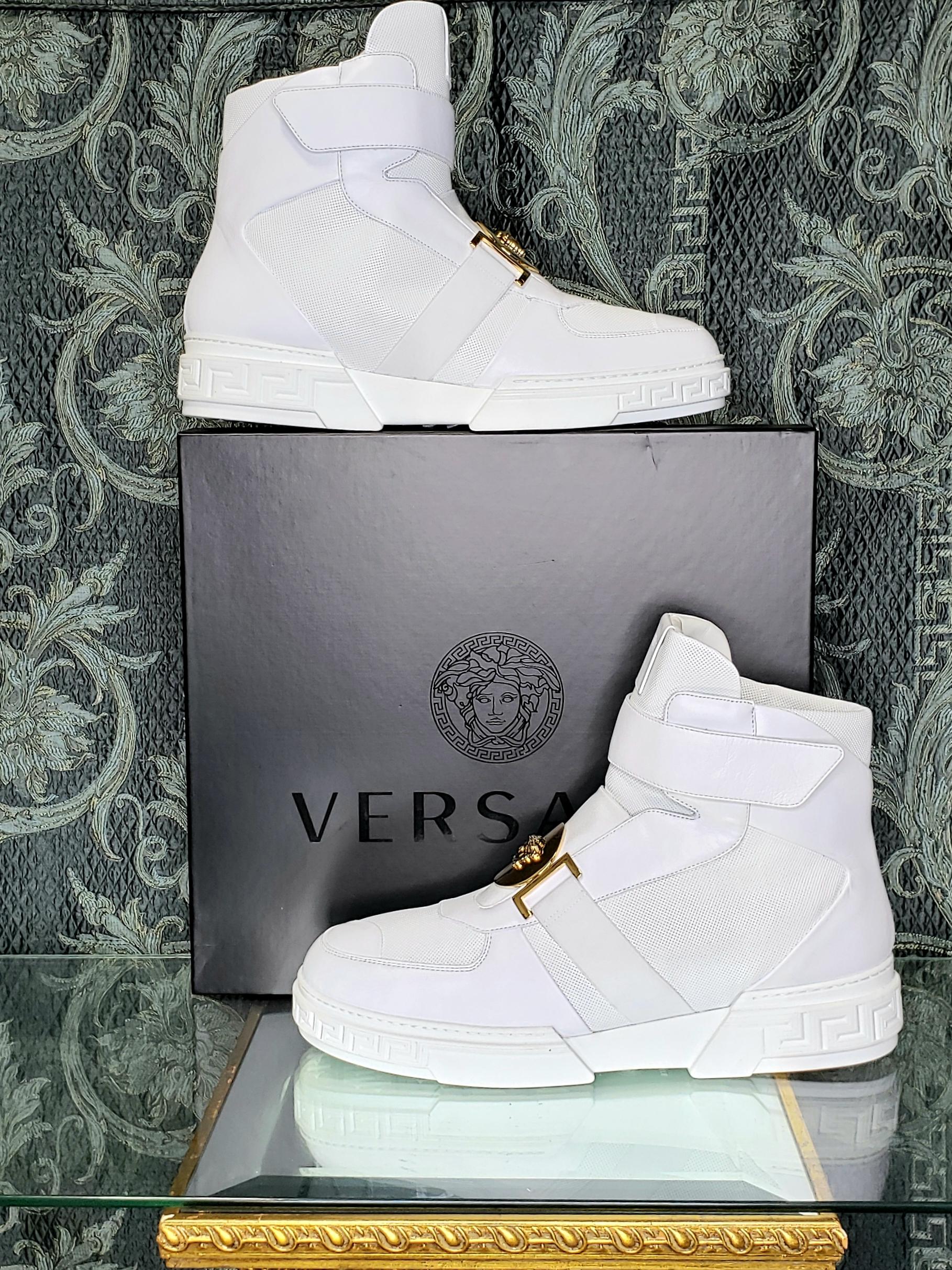 VERSACE 



White high-top sneakers from Versace. 

Made of leather.

 Decorated with a perforation. 

Velcro fastening.

 Round element with embossed gold-tone signature Medusa head on the front. 

White rubber sole with embossed Greek