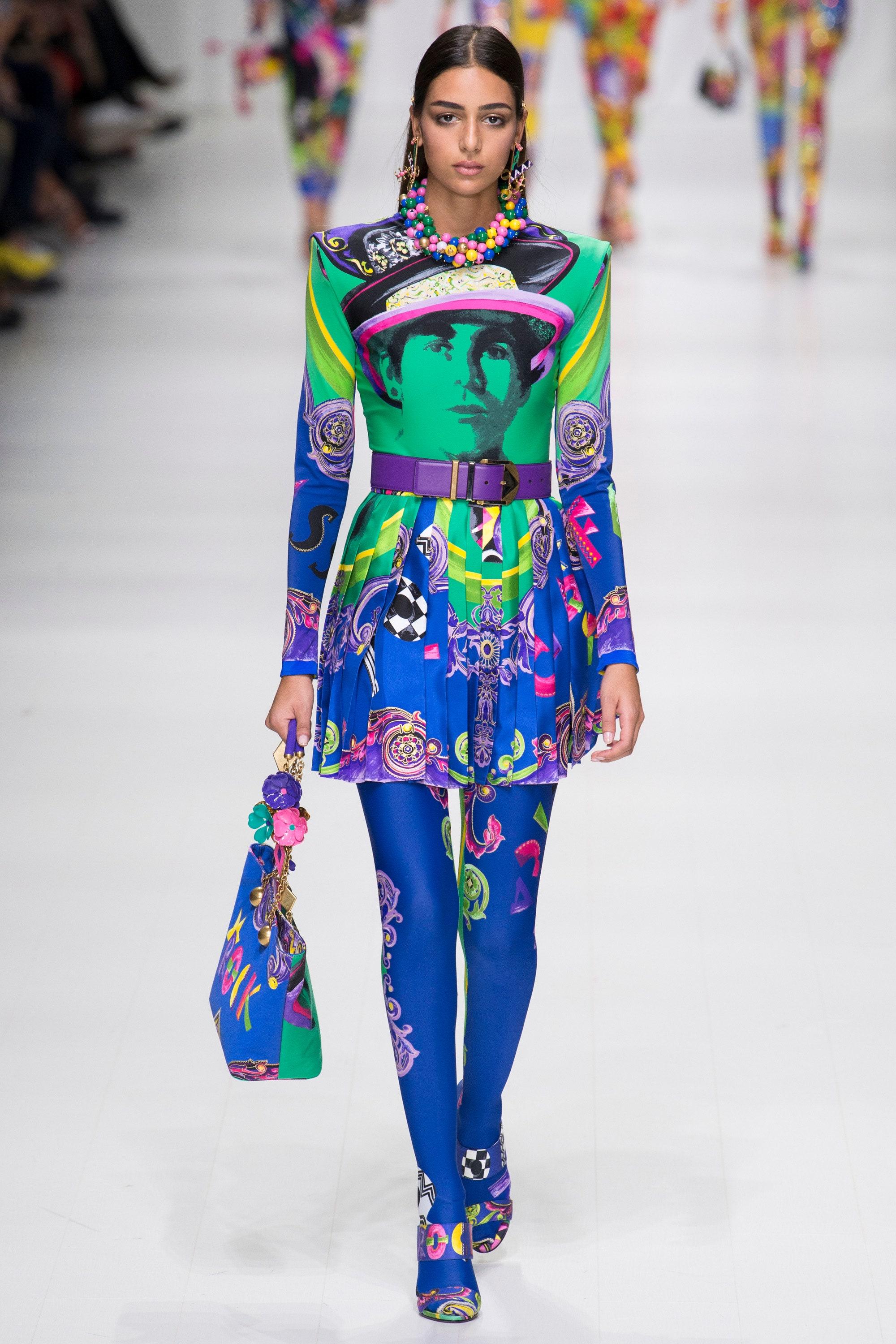 VERSACE

S/S 2018 Look # 55 
Tribute 1990 Pop Art Vogue print 3D enamel flower chain tote
Brand: Versace
Designer: Donatella Versace
Collection: Spring Summer 2018
Model Name / Style: Vogue tote
Material: Fabric
Color: Multicolour
Pattern: Abstract;