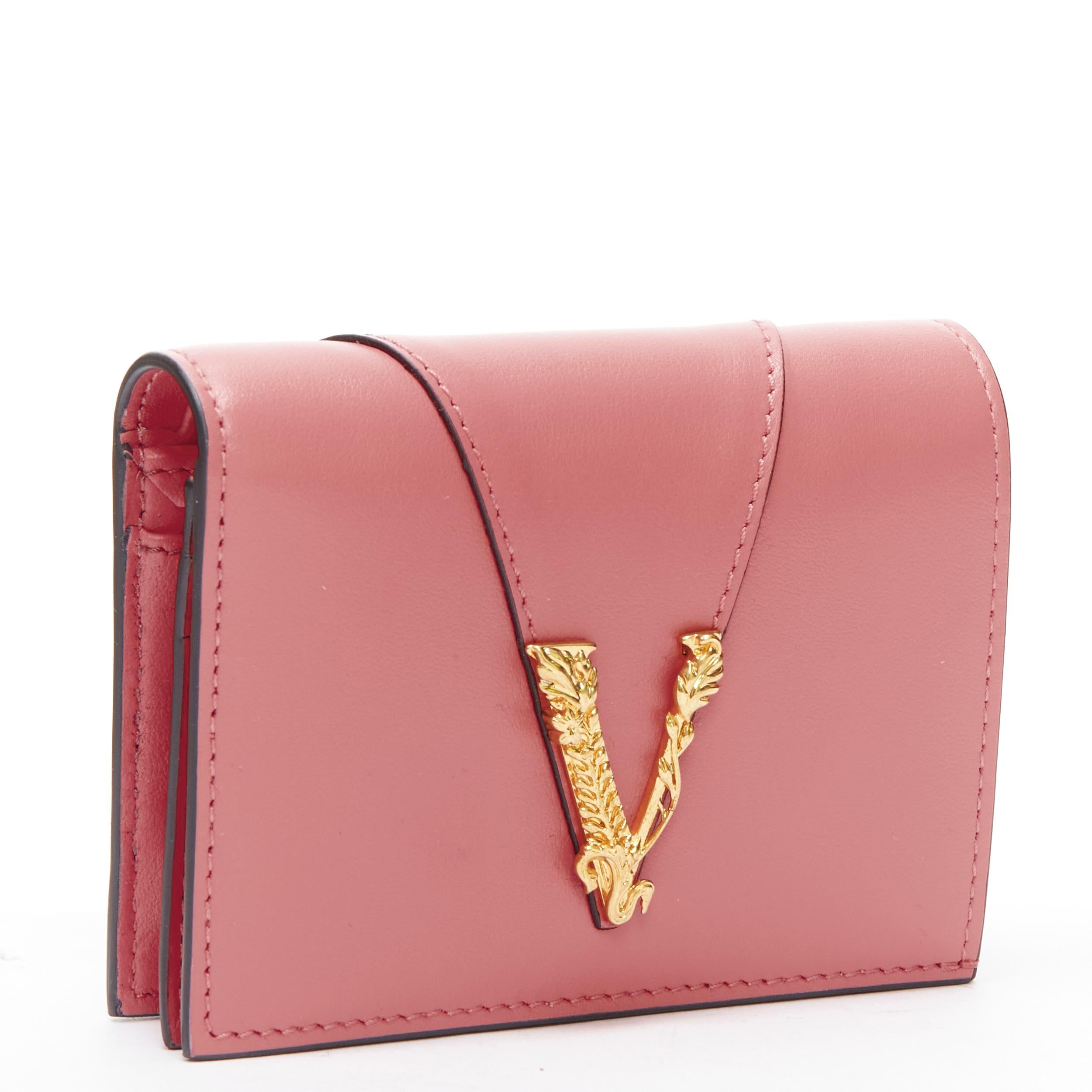 new VERSACE Virtus V pink leather zip bi fold cardholder short wallet 
Reference: TGAS/B02063 
Brand: Versace 
Designer: Donatella 
Versace Material: Leather 
Color: Pink 
Pattern: Solid 
Closure: Button 
Extra Detail: 4-card slot. Zip compartment.
